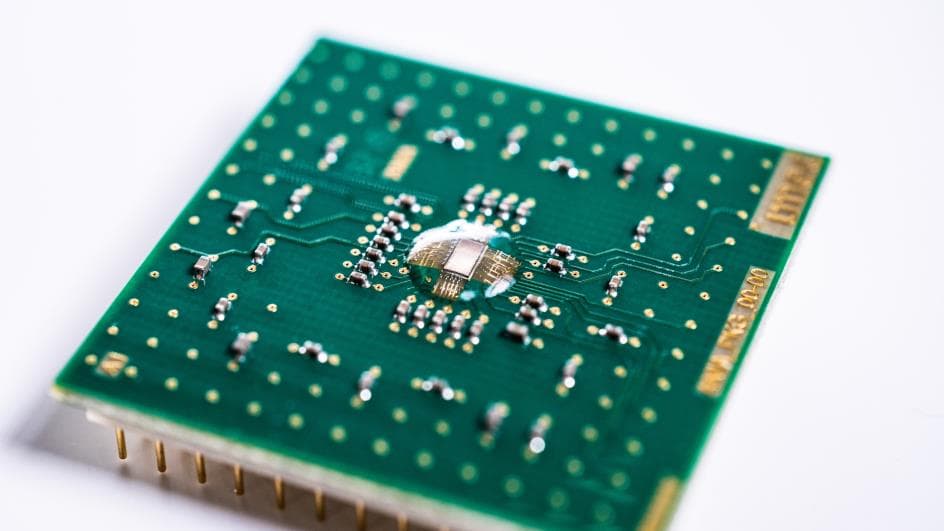 De%20Analoge%20Inferentie%20Accelerator%20%28AnIA%29%20is%20een%20energiezuinige%20chip%20die%20slimme%-8cd1b506c317 Green chip board with a central exposed die and soldered components on a white background