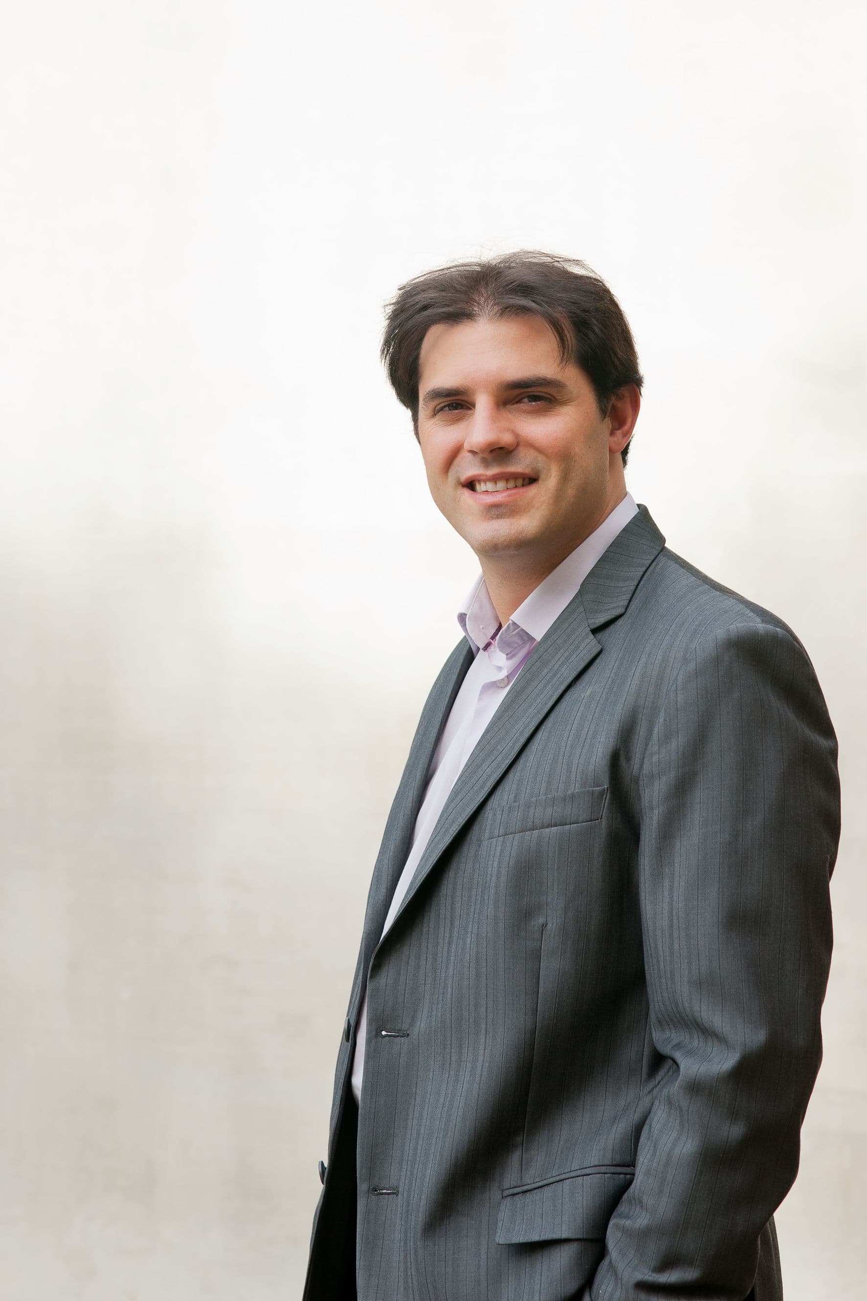 denis_marcon_lr Portrait of Denis Marcon in a gray suit, smiling against a light background