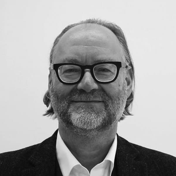 Dieter%20Hoffend Portrait of Dieter Hoffend, wearing glasses and a blazer, against a plain background