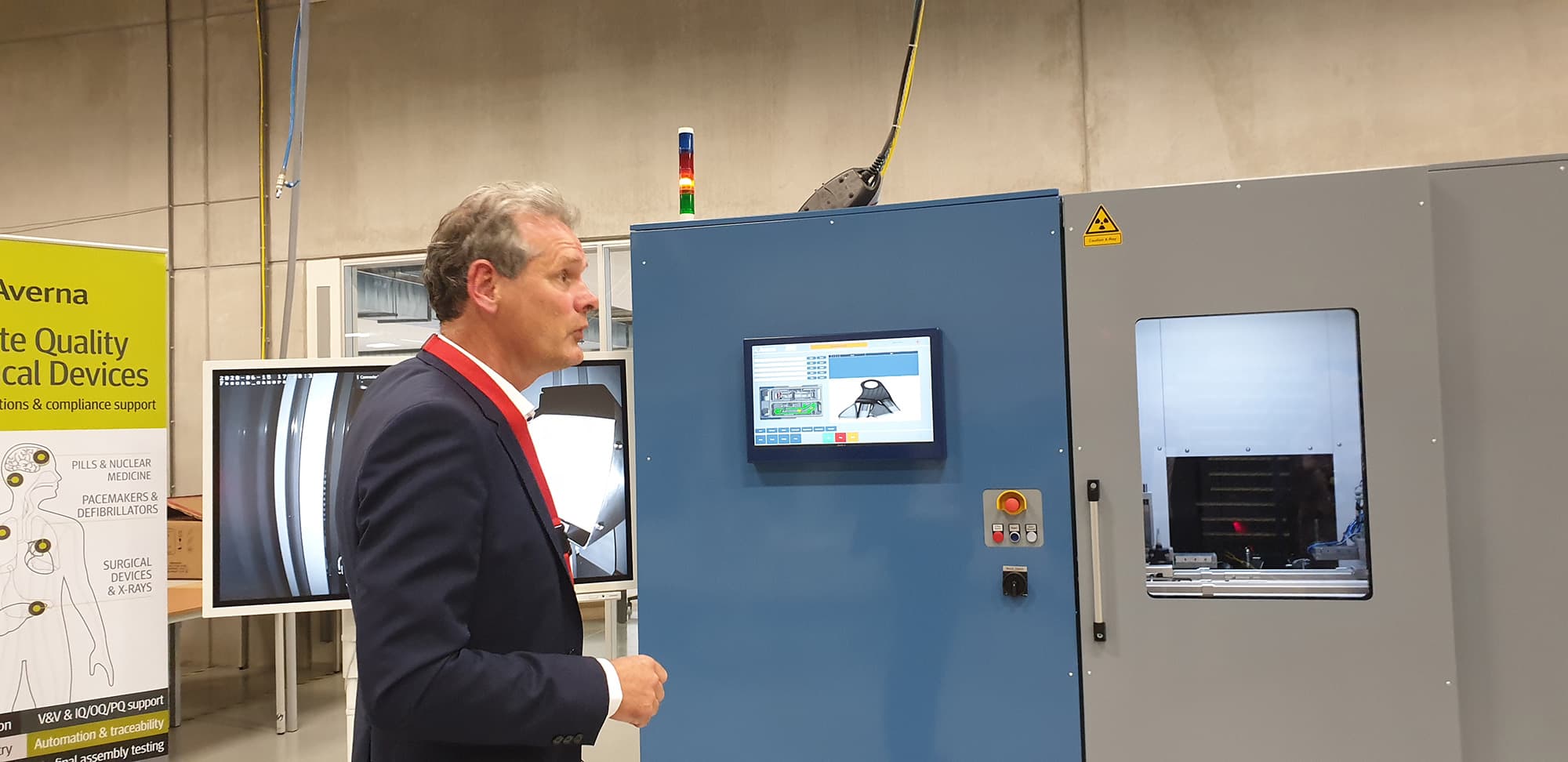 dirk_hamelinck_ceo_deltaray Dirk Hamelinck stands beside an industrial inspection machine in a manufacturing lab.