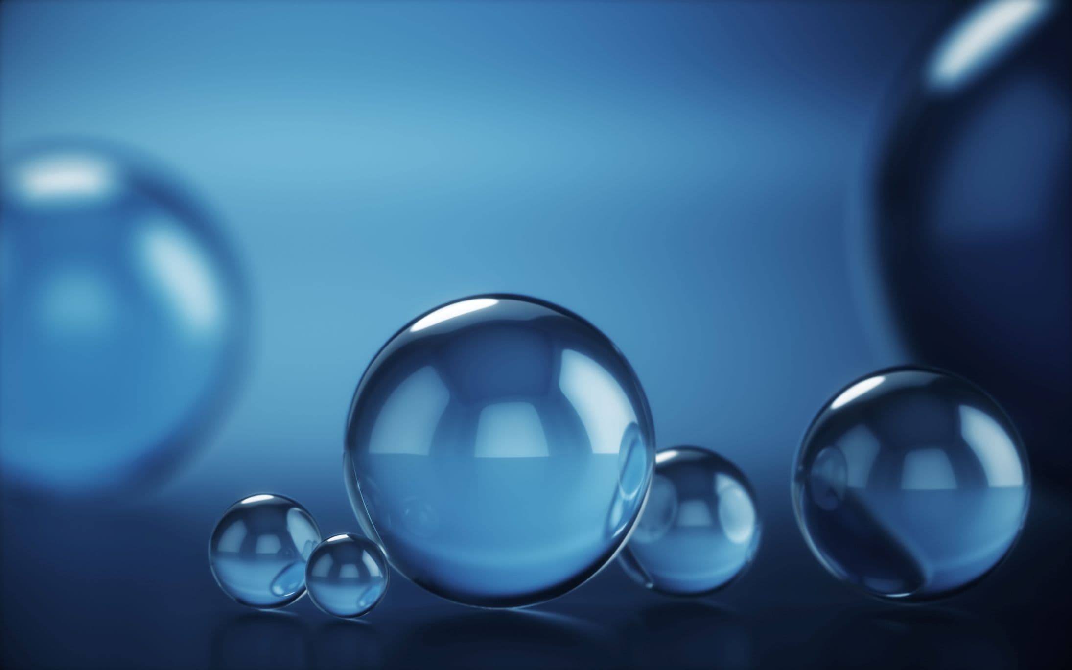 Glowing blue droplets with central large droplet Glowing blue droplets on a dark background, with one large droplet centered among smaller ones
