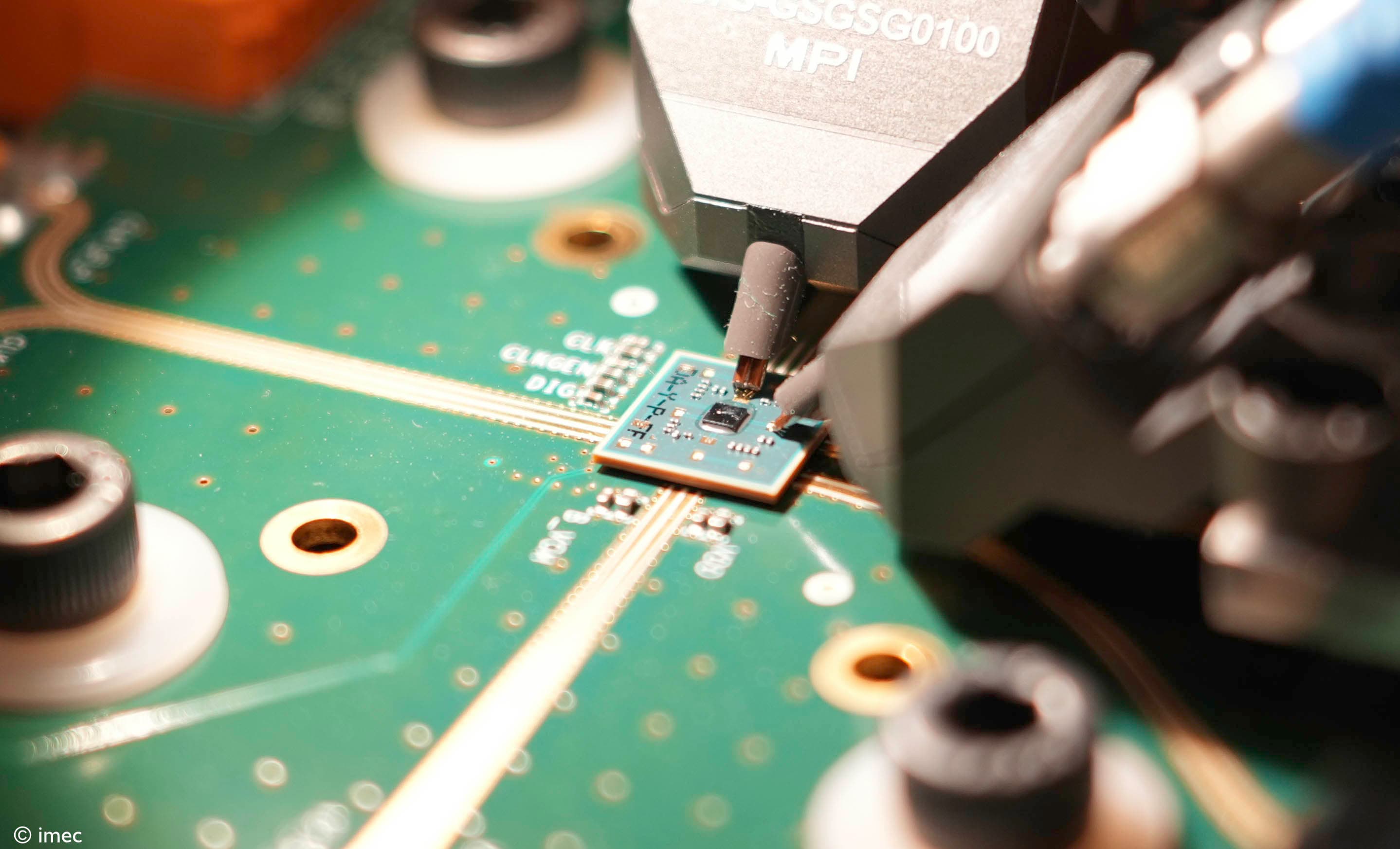 DSC02392_cropped Close-up of a circuit board with a small chip being tested by probing equipment.