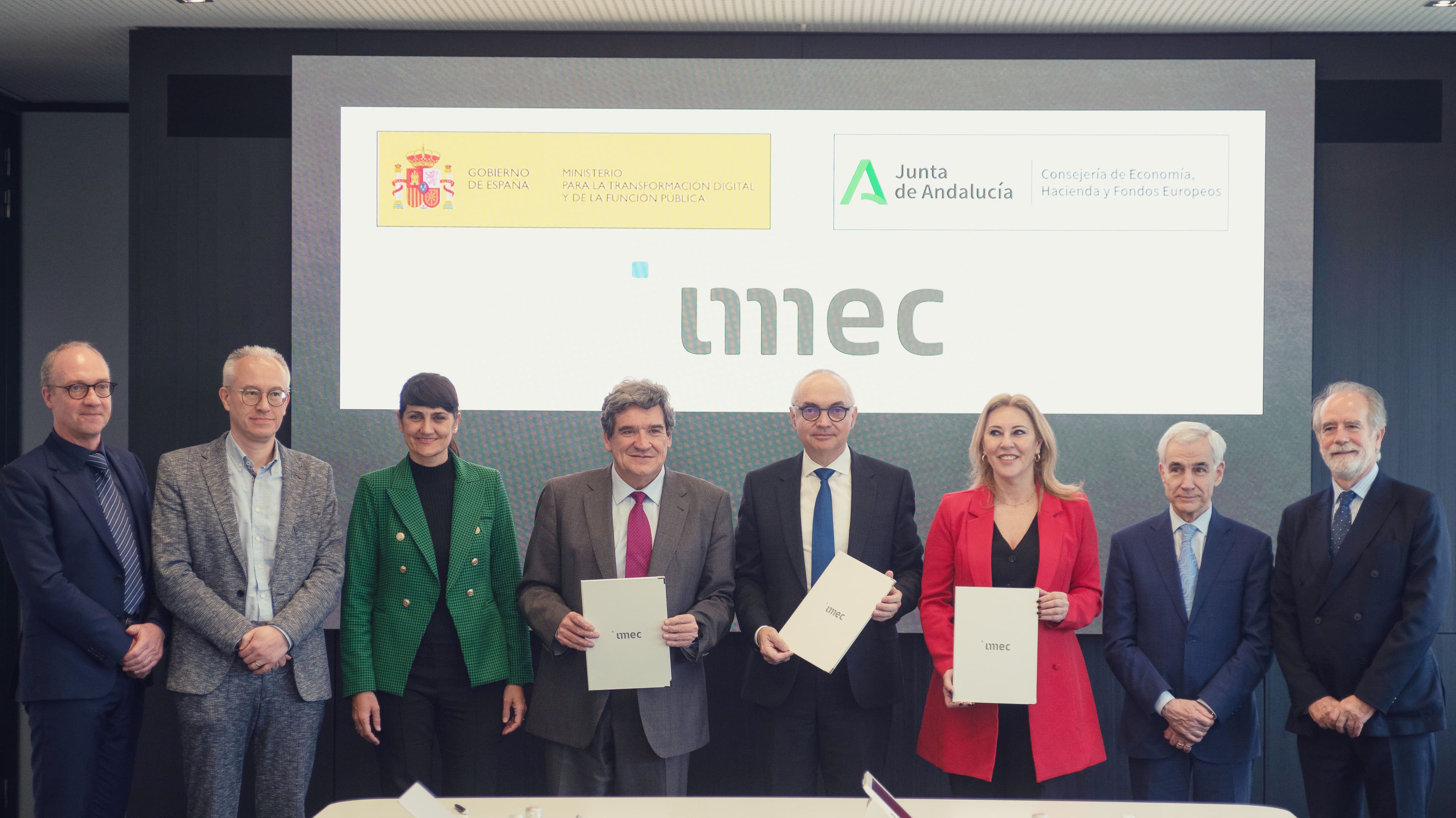 Group of officials posing with imec folders Group of officials posing with imec folders in front of Spanish government, Andalusia and imec logos
