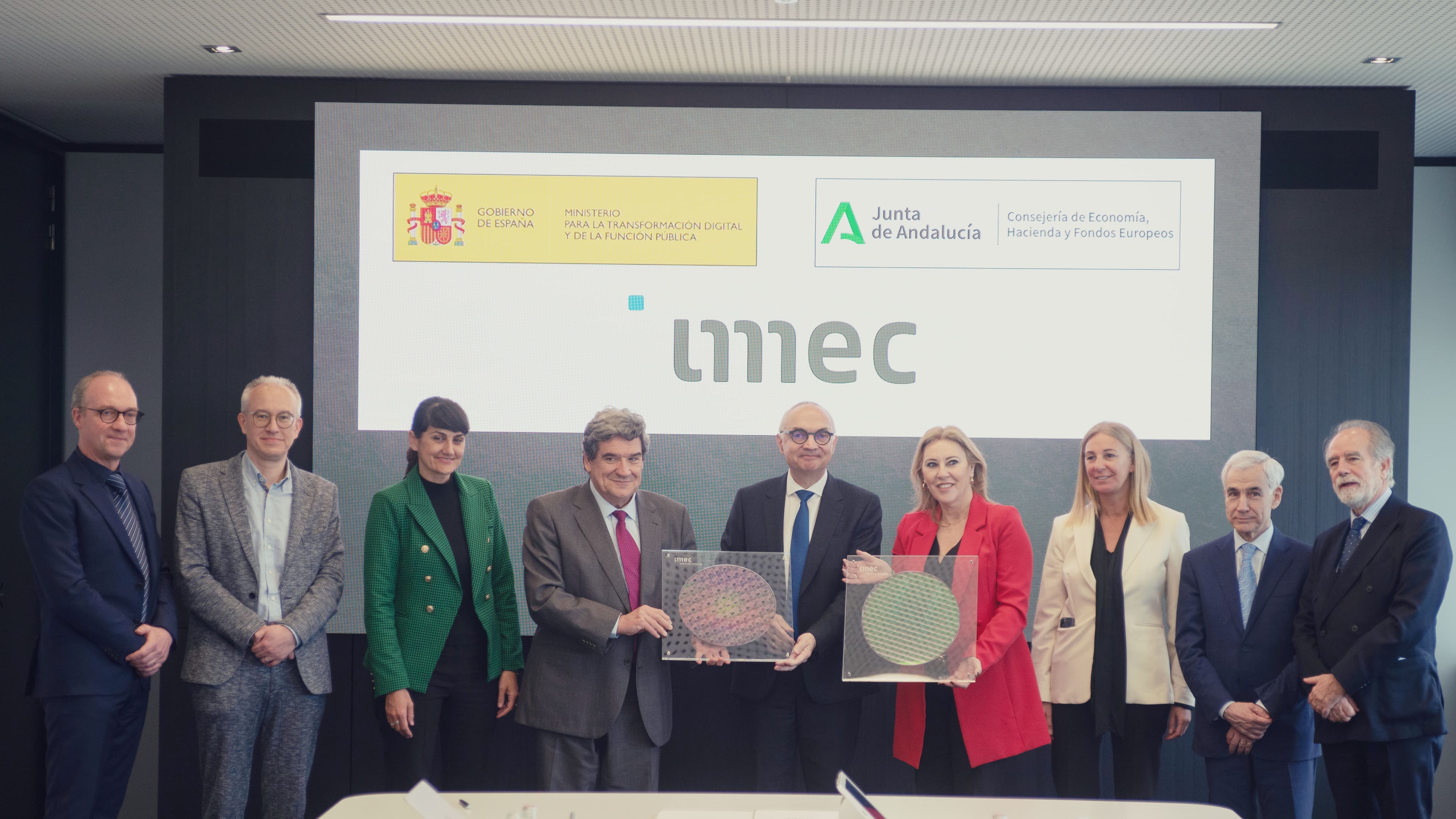 DSC02523 Group of officials posing in front of an imec backdrop, holding semiconductor wafer plaques after signing an MoU.