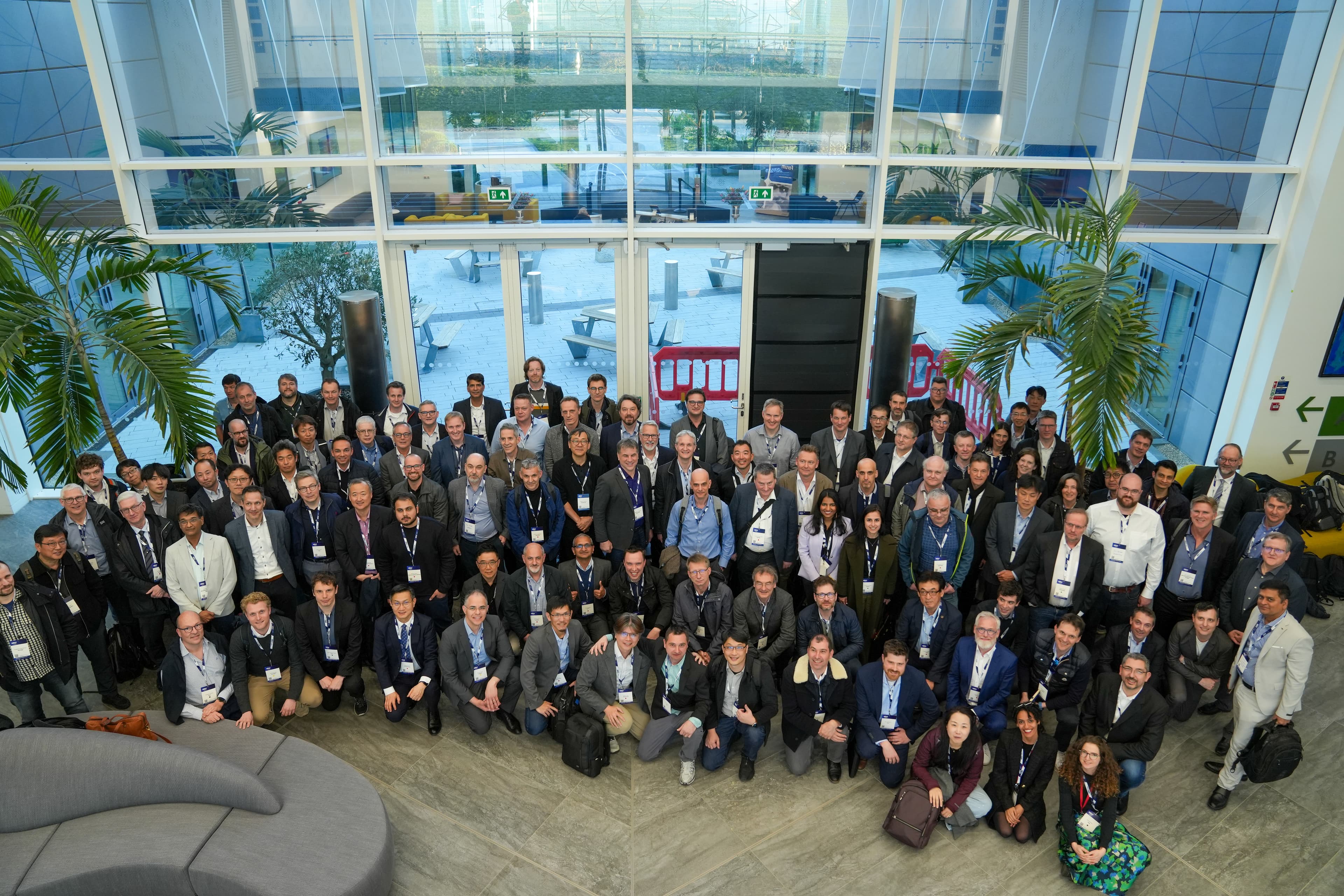 Conference attendees group photo at Automotive Chiplet Forum Large group of conference attendees posing in a lobby at the Automotive Chiplet Forum