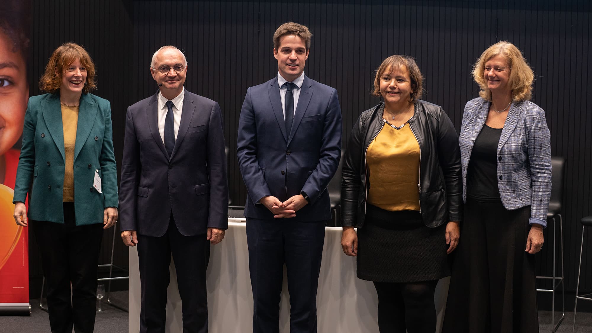 DSC08658 Five speakers pose on stage at a GSK and imec event.