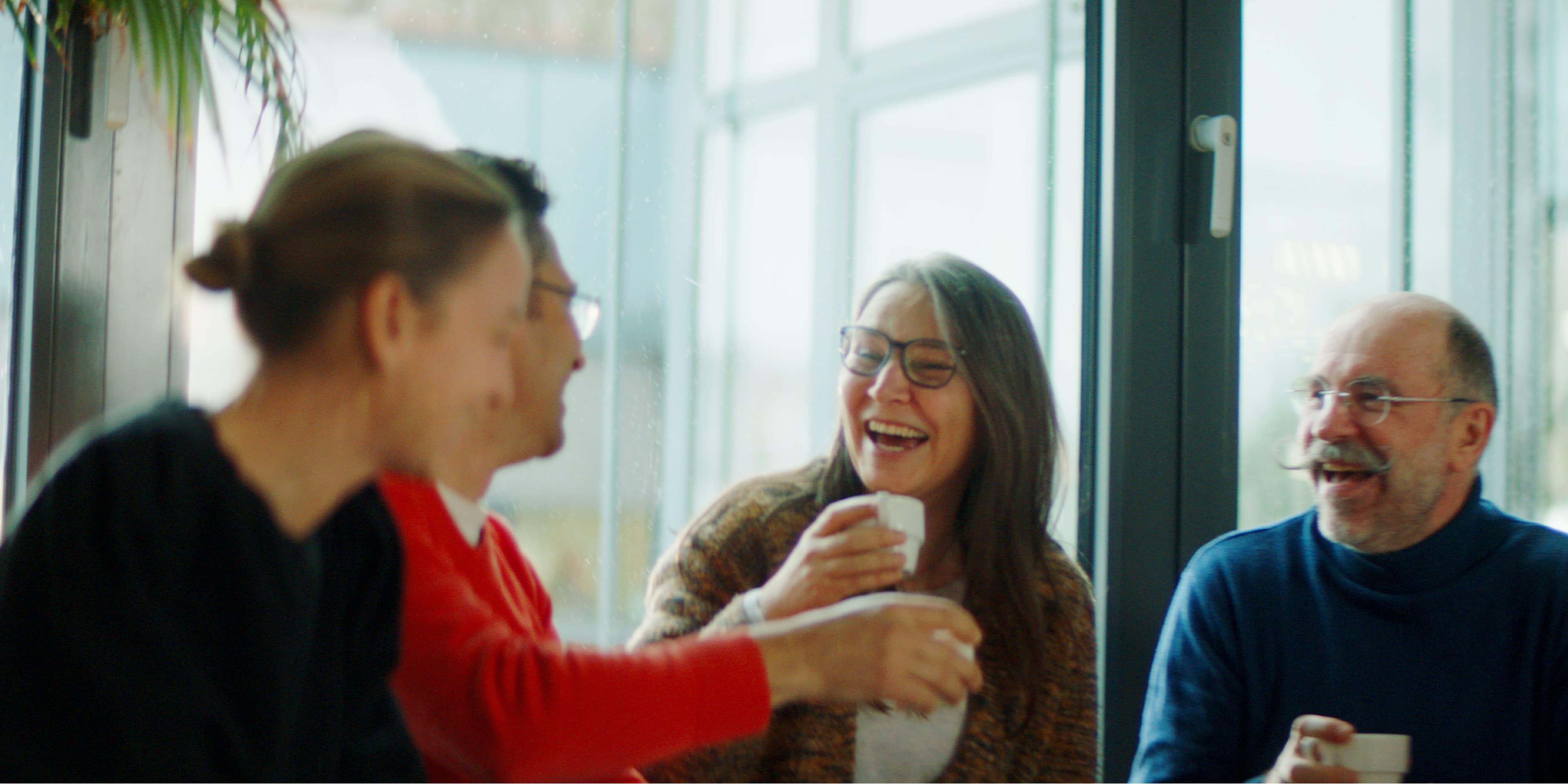 colleagues laughing together over coffee in bright office corridor Colleagues laughing together over coffee in a bright office corridor