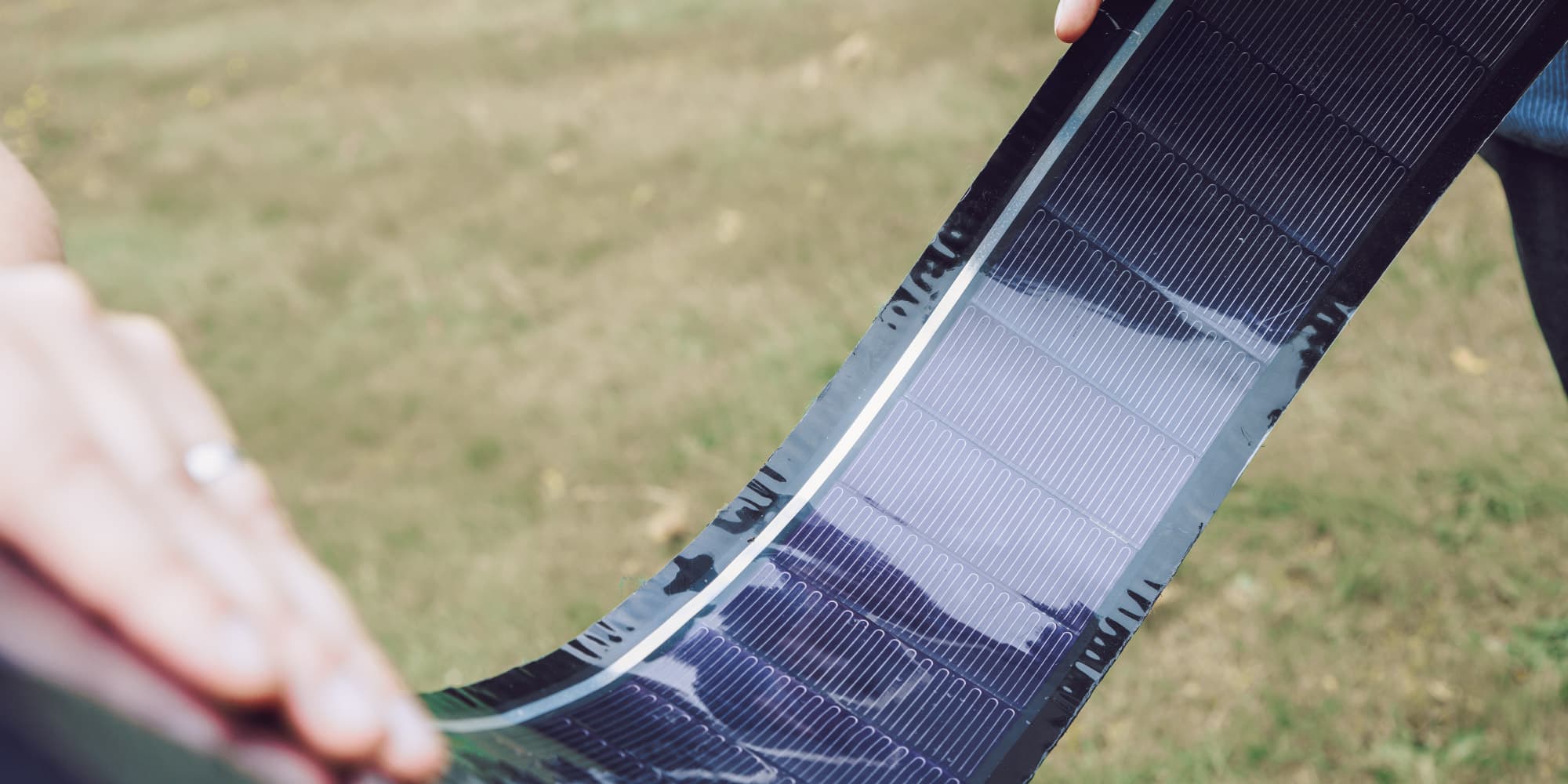 Enfoil-flexible-solar-panels Hands holding a thin, flexible solar panel outdoors