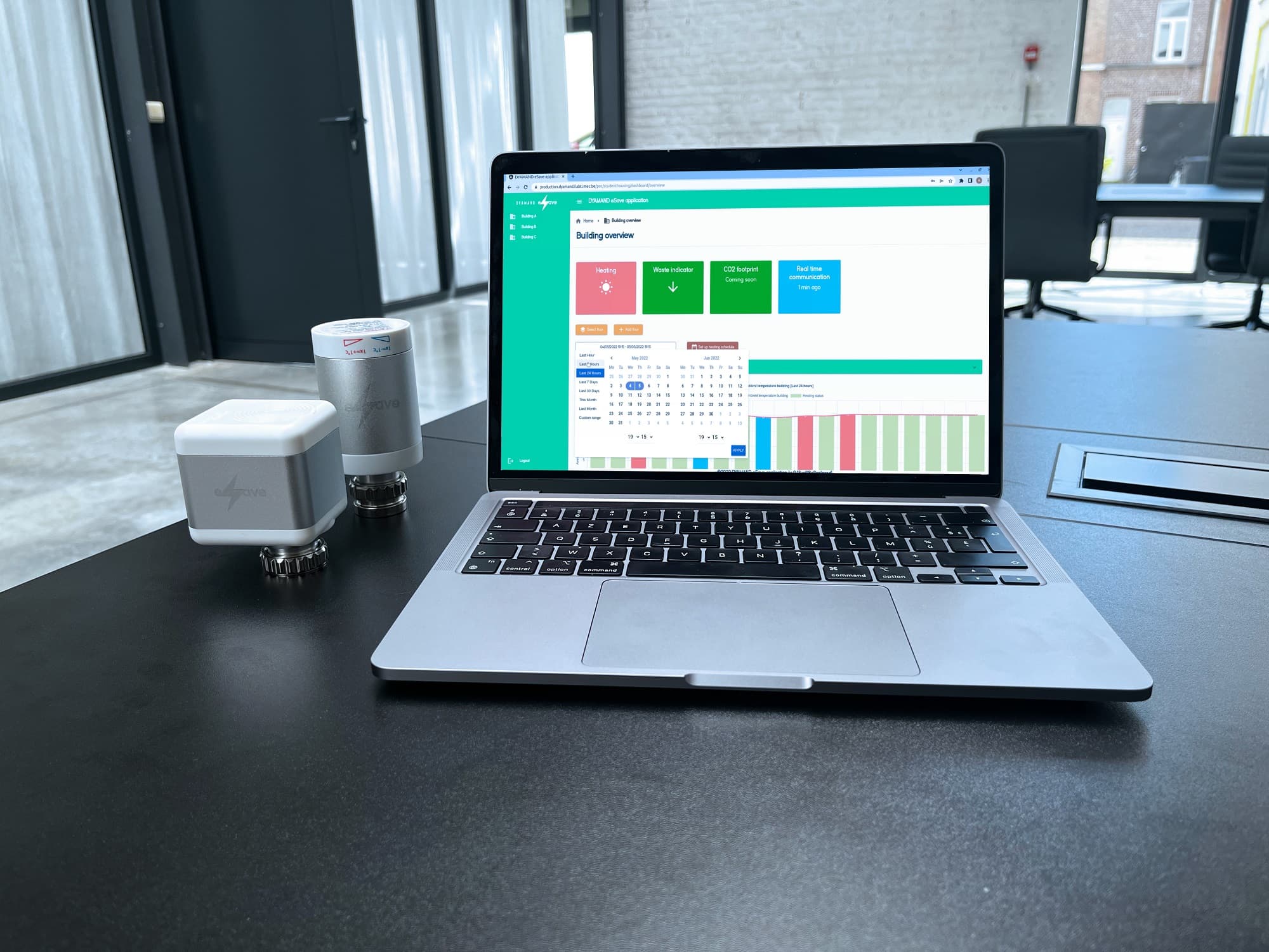 eSave_Valve_App_header Laptop showing the eSave building overview dashboard beside two smart radiator valves