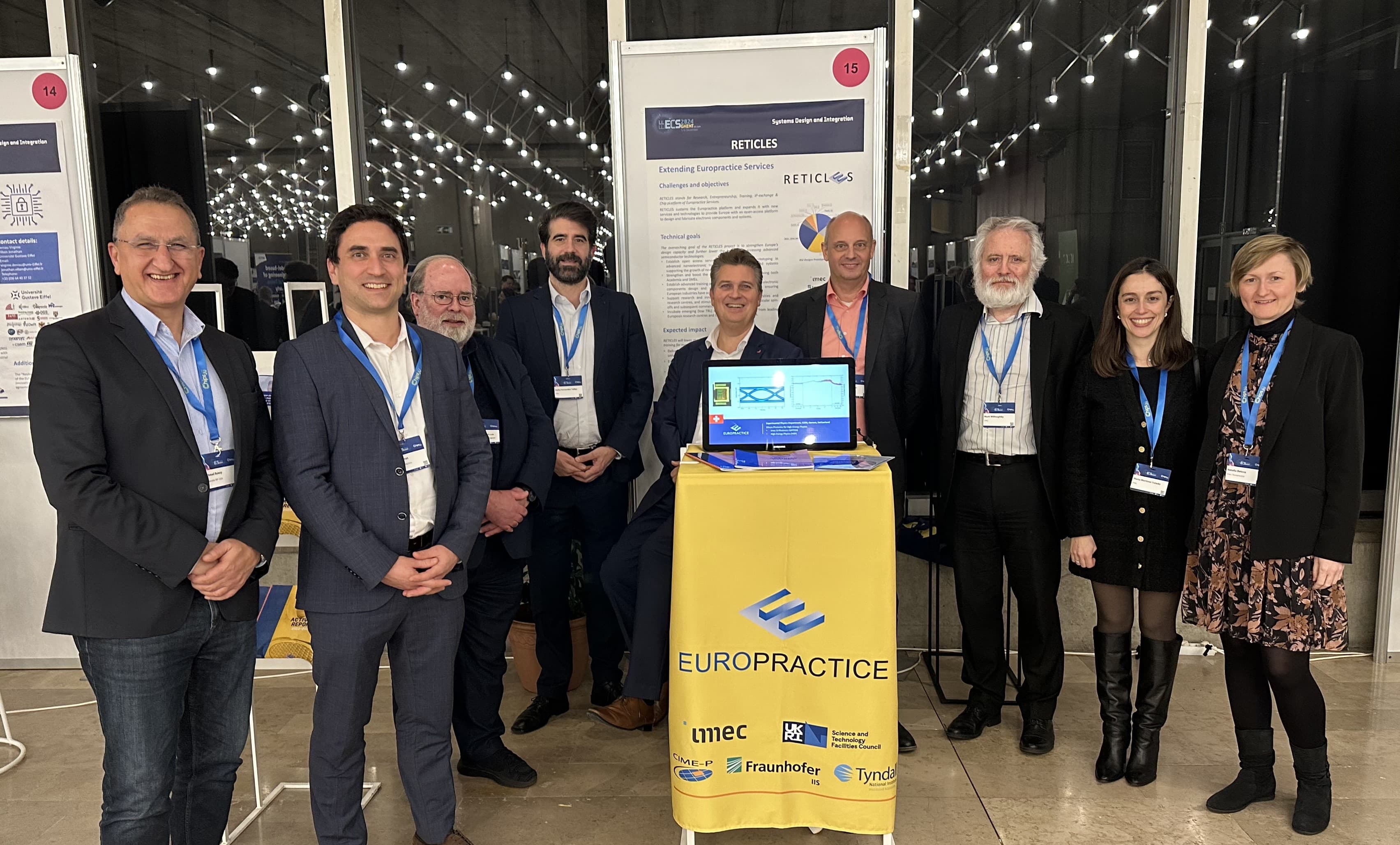 Europractice%20members Europractice team members posing at a conference booth in front of posters and a yellow Europractice banner