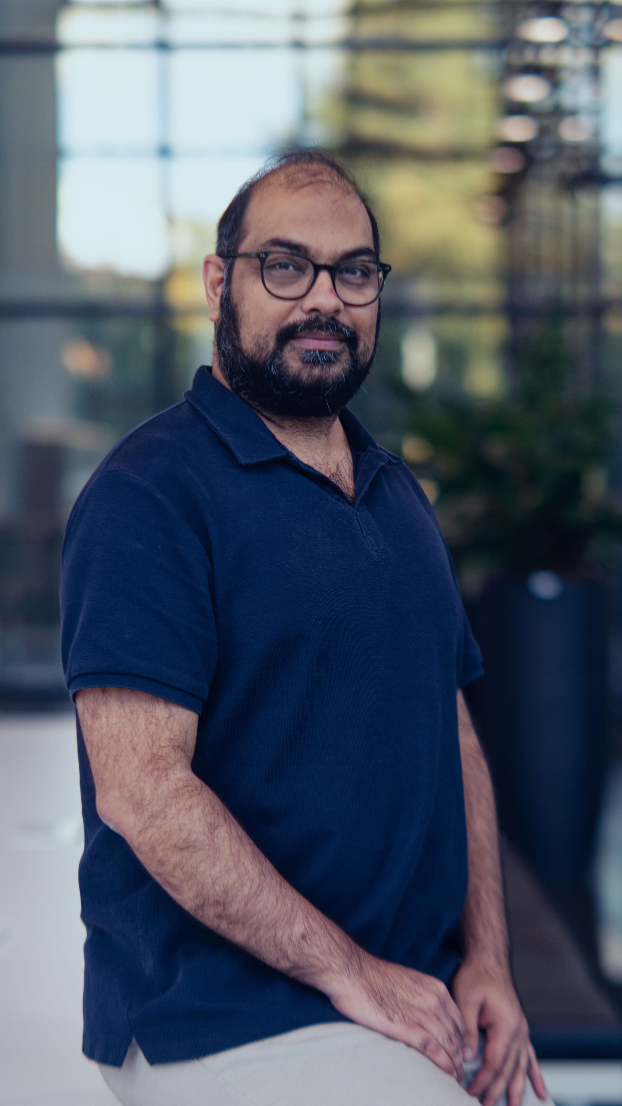 Farrukh%20Yasin Portrait of Farrukh Yasin standing outdoors in a navy polo shirt and glasses