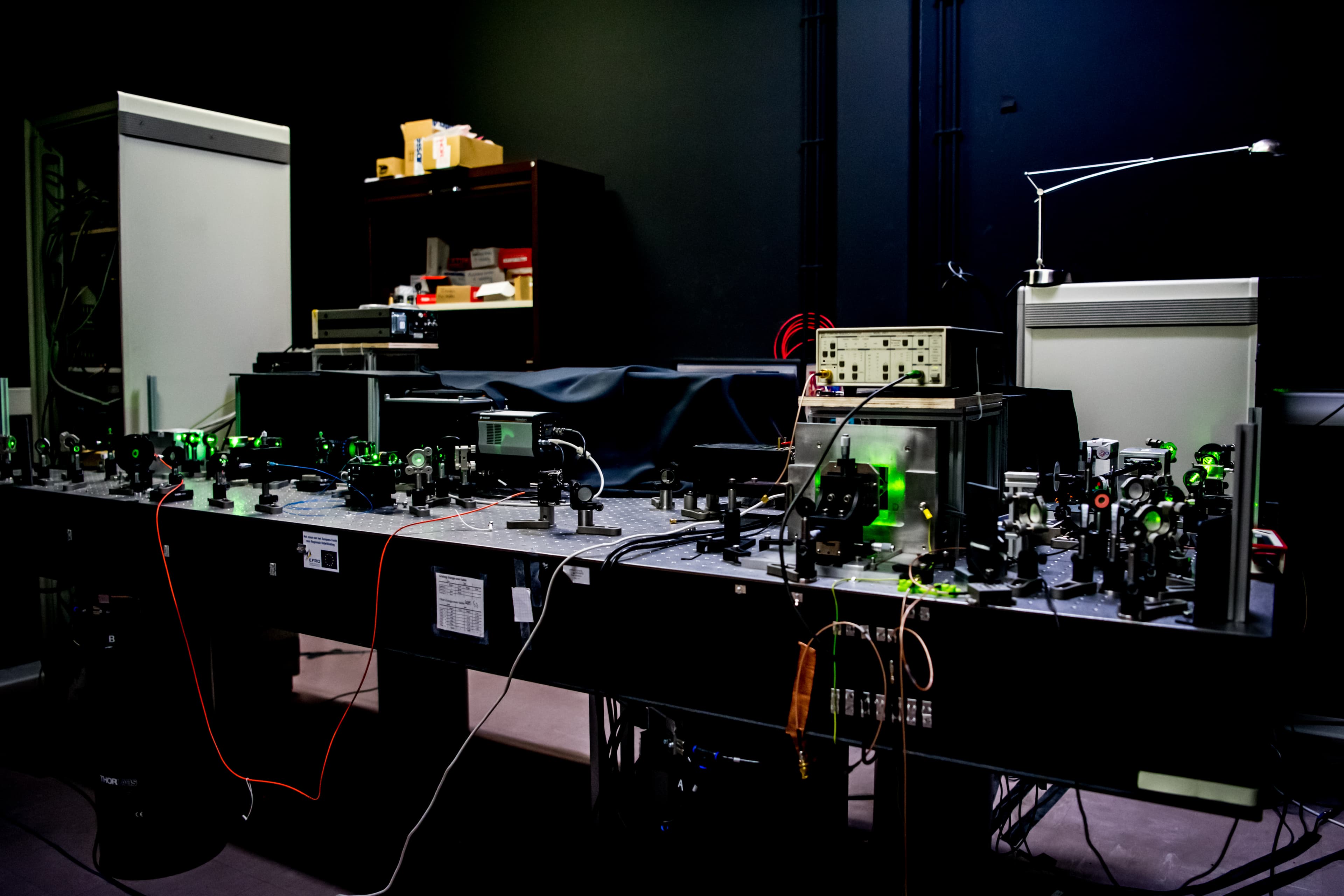 Fig%201%20Milos_Nesladek_en_team_06 Optical table with a room-temperature quantum microscope setup and lasers in a dark lab