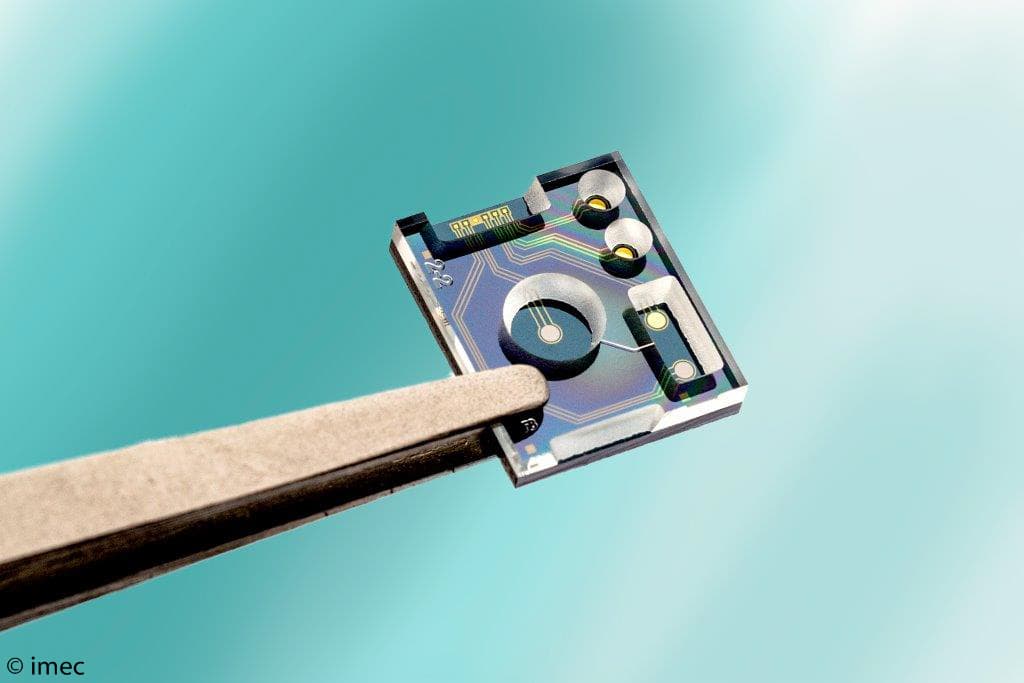 Microchip sensor held by tweezers Microchip sensor held by tweezers against a teal background