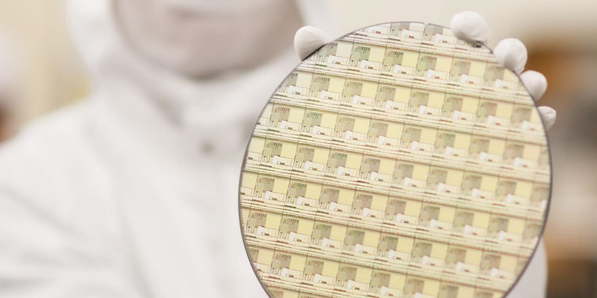 GaN_imec_1 Gloved researcher holding a semiconductor wafer with a patterned chip array.