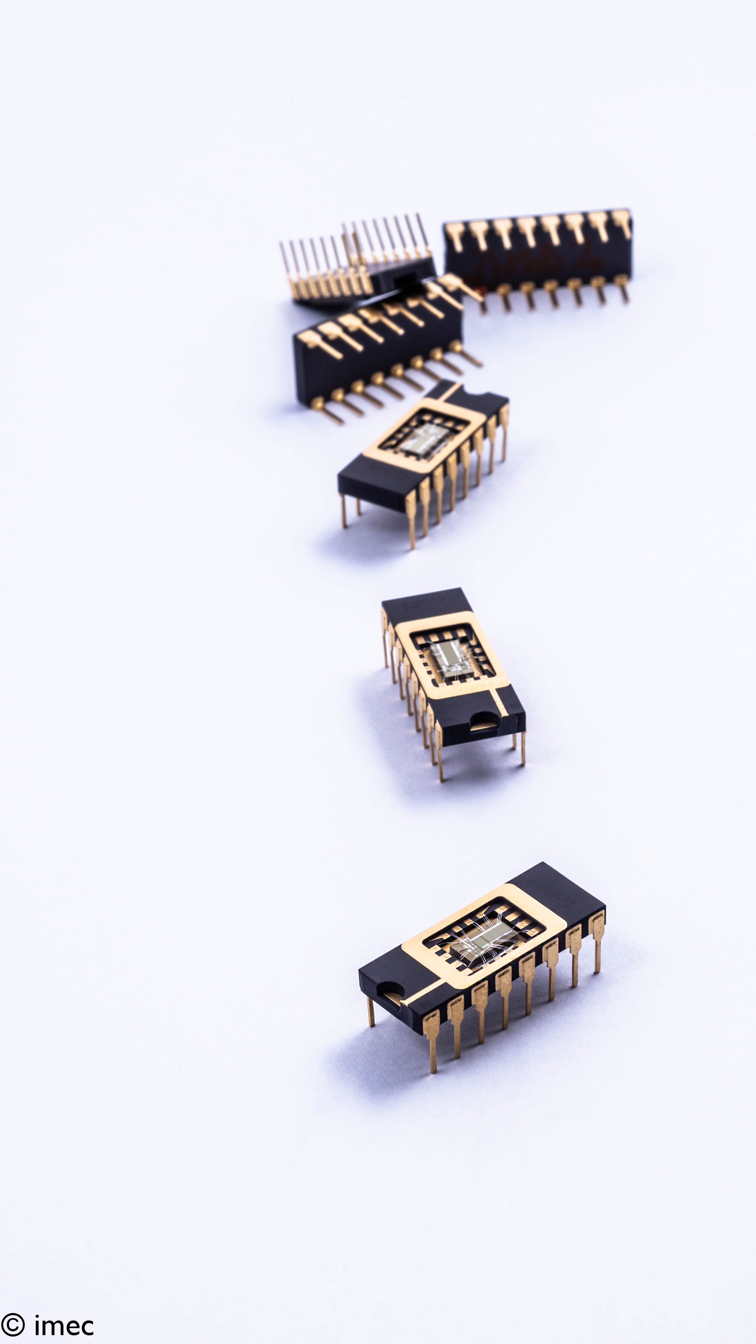 Black and gold semiconductor chips with wire bonds Four black-and-gold semiconductor chips with exposed wire bonds arranged diagonally on a white background