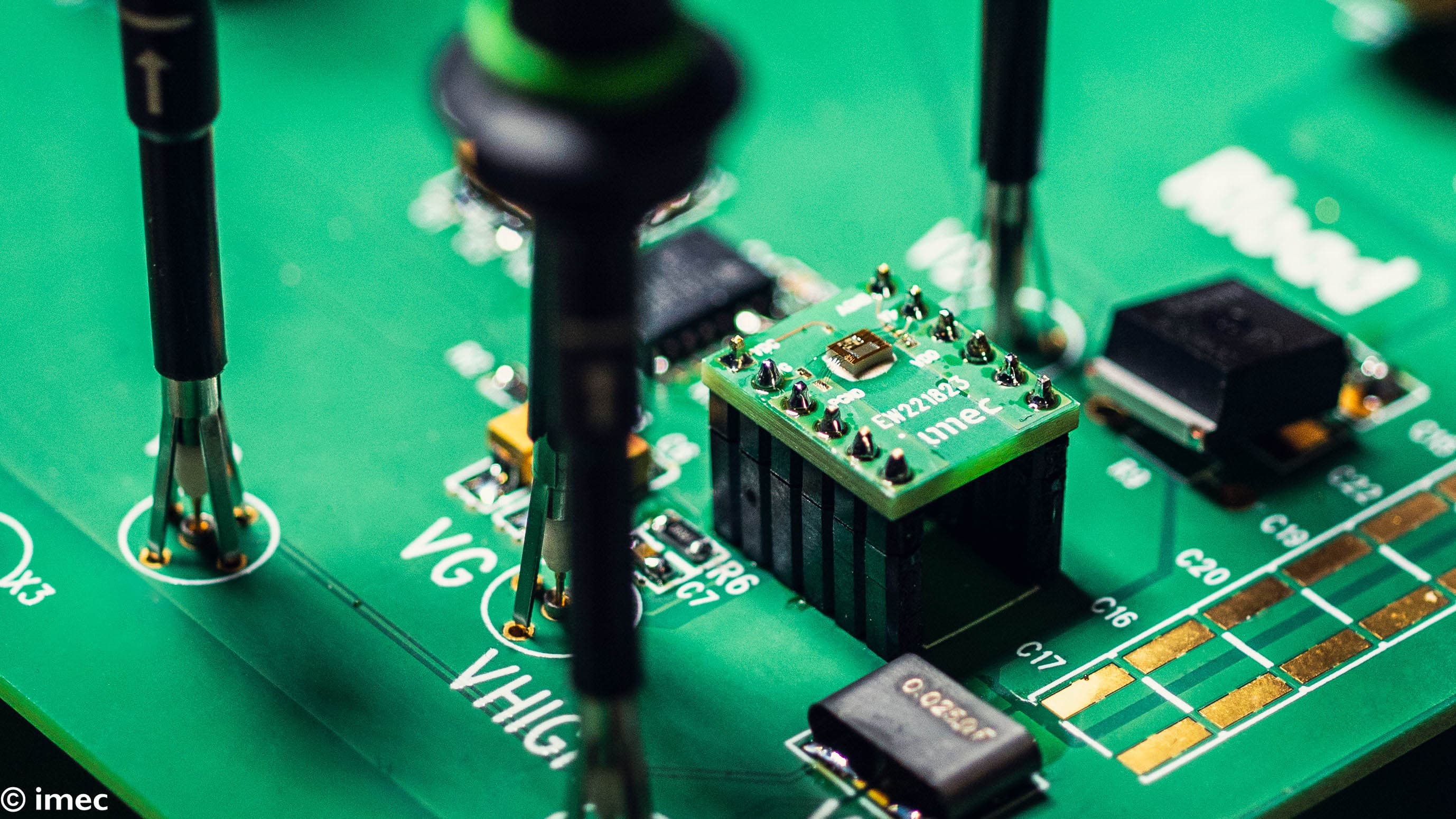 close-up of electronic circuit board with probes Close-up of a green circuit board with mounted electronic components and test probes in a lab setup.