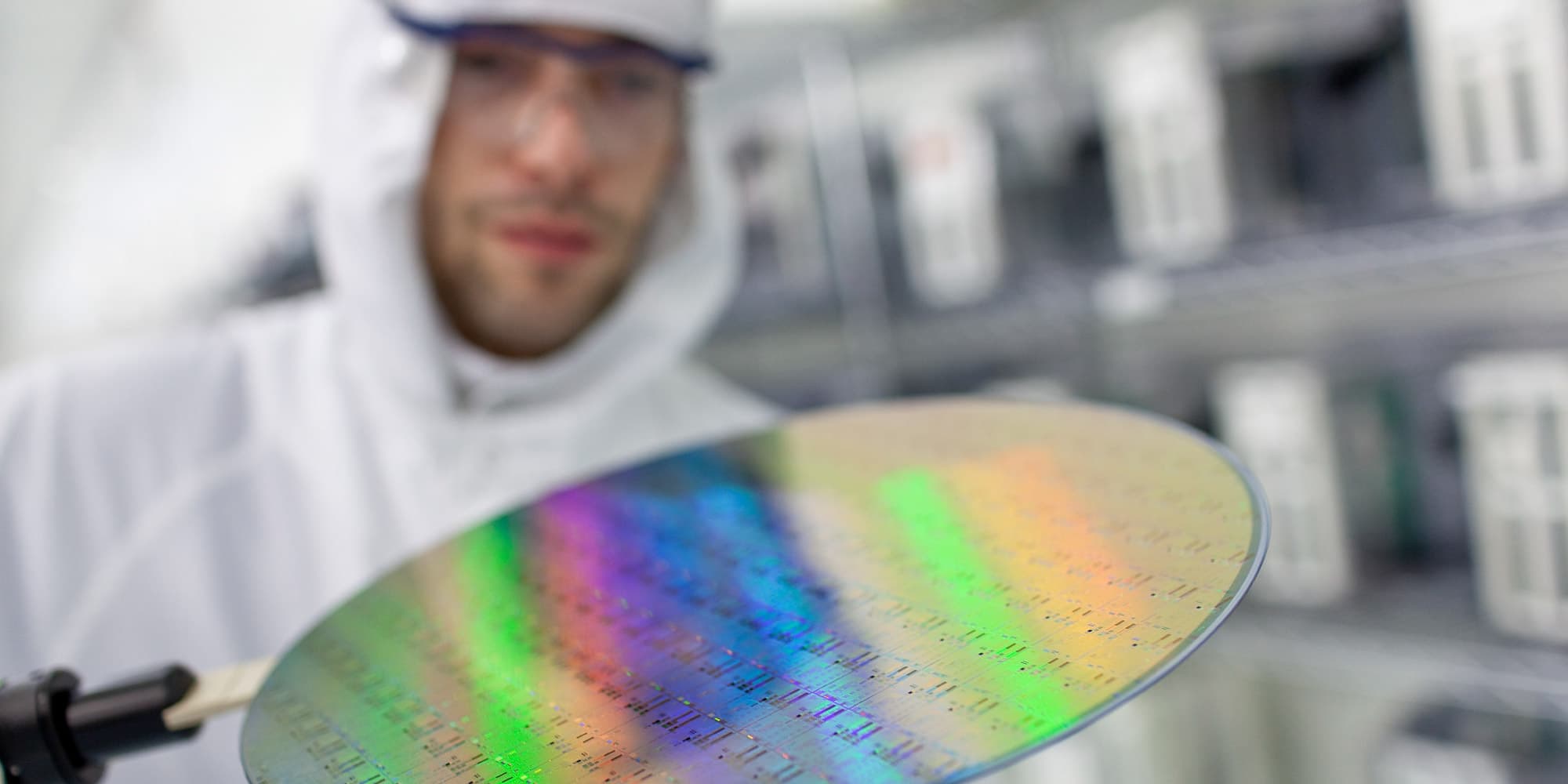 gate_stack_reliability Researcher in a cleanroom holding a reflective semiconductor wafer