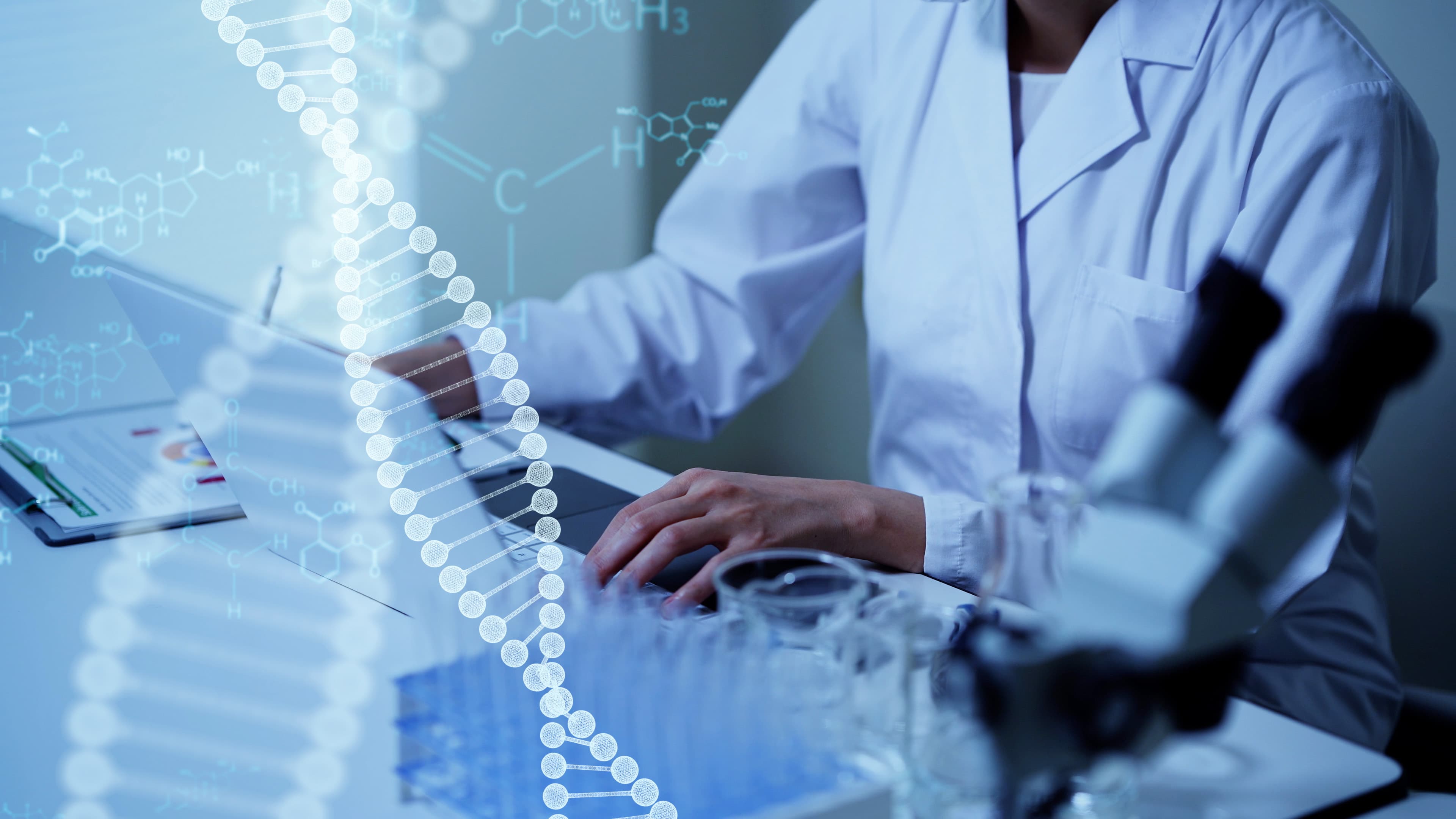GettyImages-1210343476 Onderzoeker in een labjas aan een bureau met een DNA-dubbelhelix-overlay
