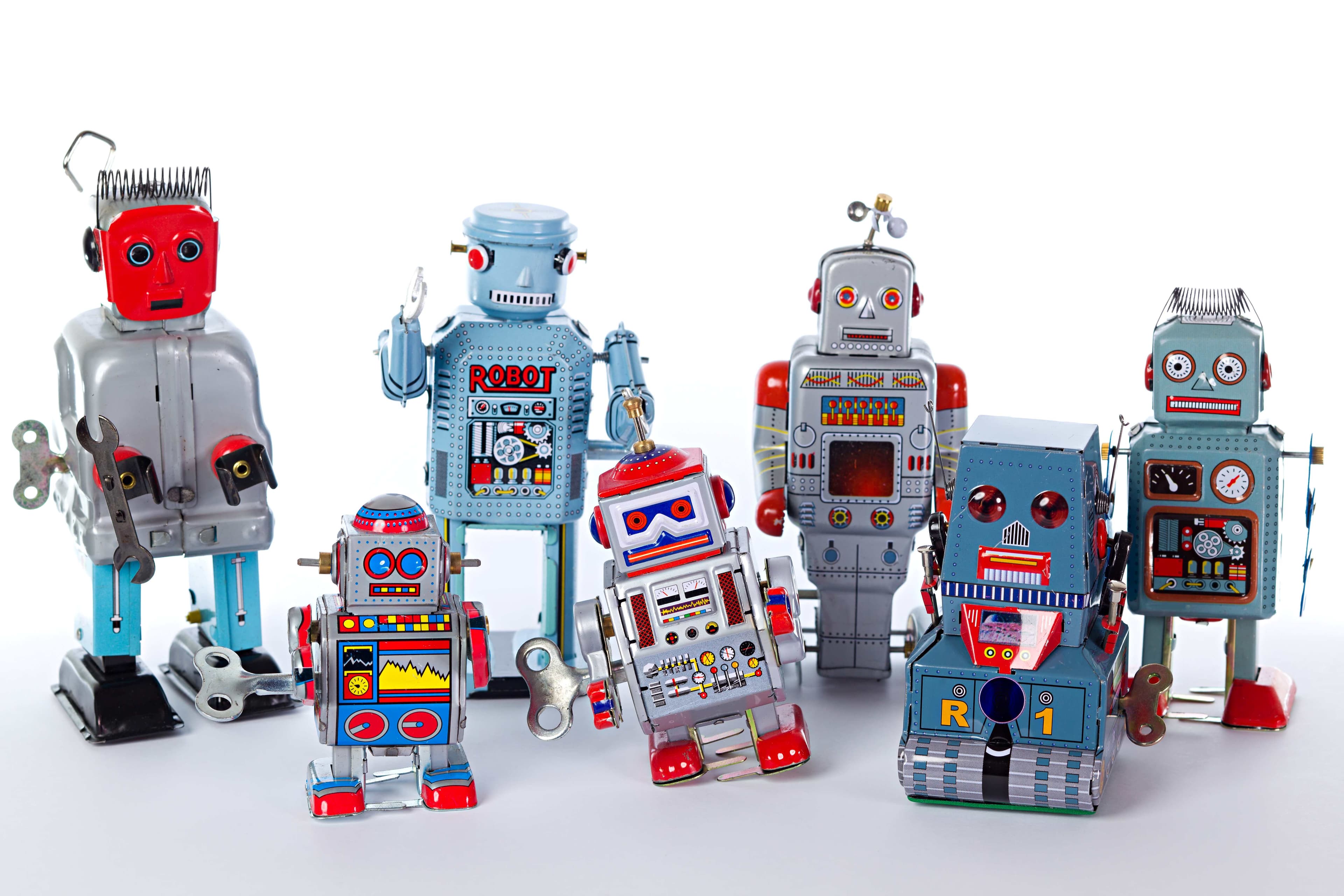 GettyImages-187310896 Een rij kleurrijke speelgoedrobots op een witte achtergrond