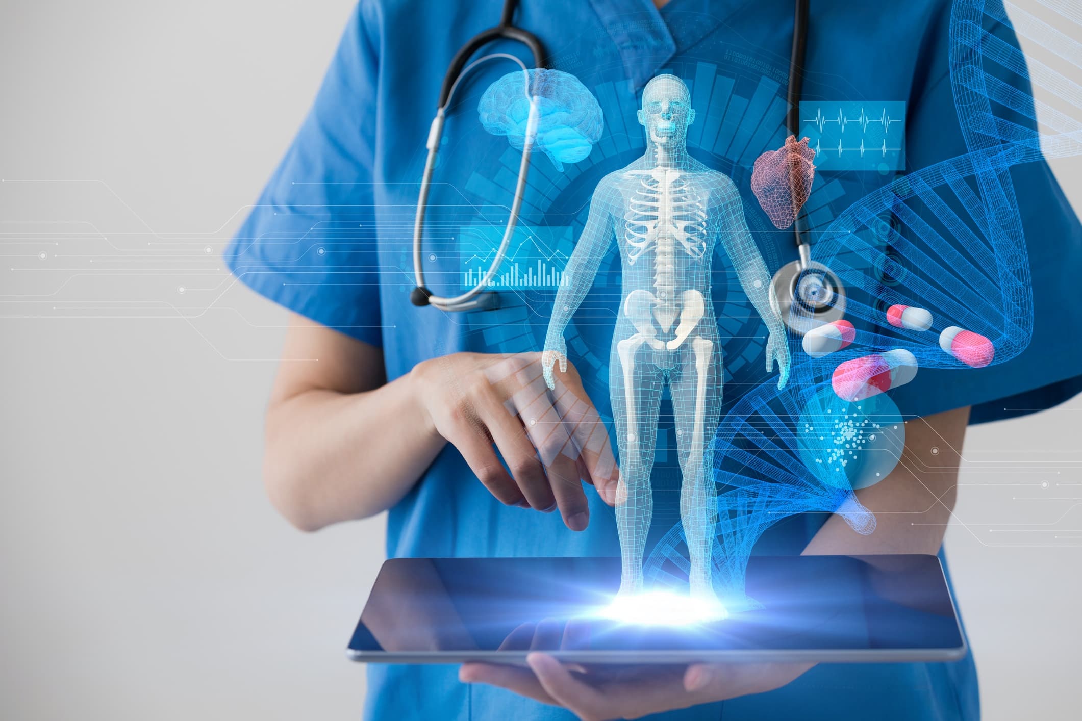 GettyImages-872676342 Zorgmedewerker in scrubs gebruikt een tablet met een digitaal menselijk lichaam en medische gegevensoverlays