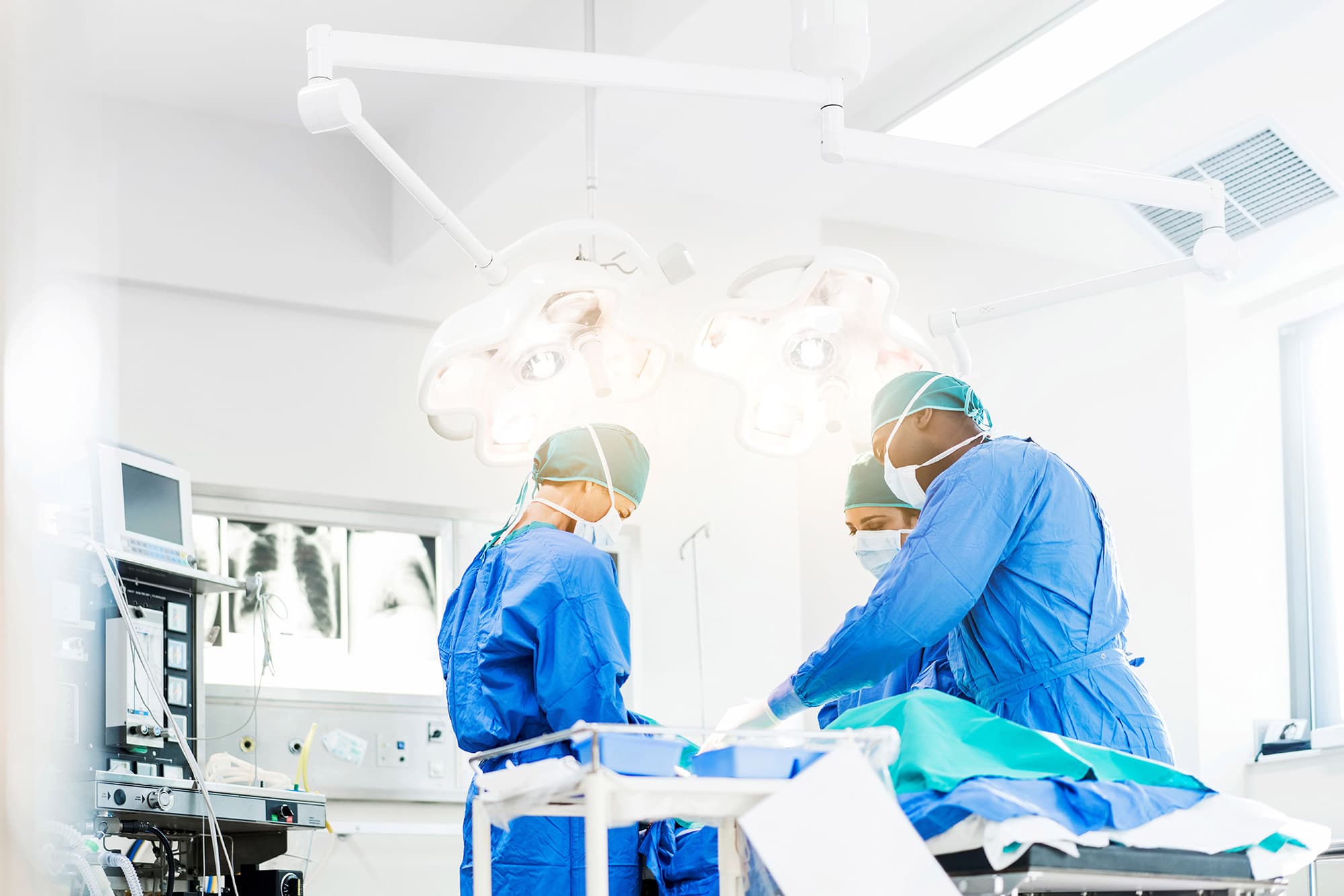 GettyImages-904805358-Fig-5_0 Chirurgen in blauwe operatiekleding werken in een lichte operatiekamer