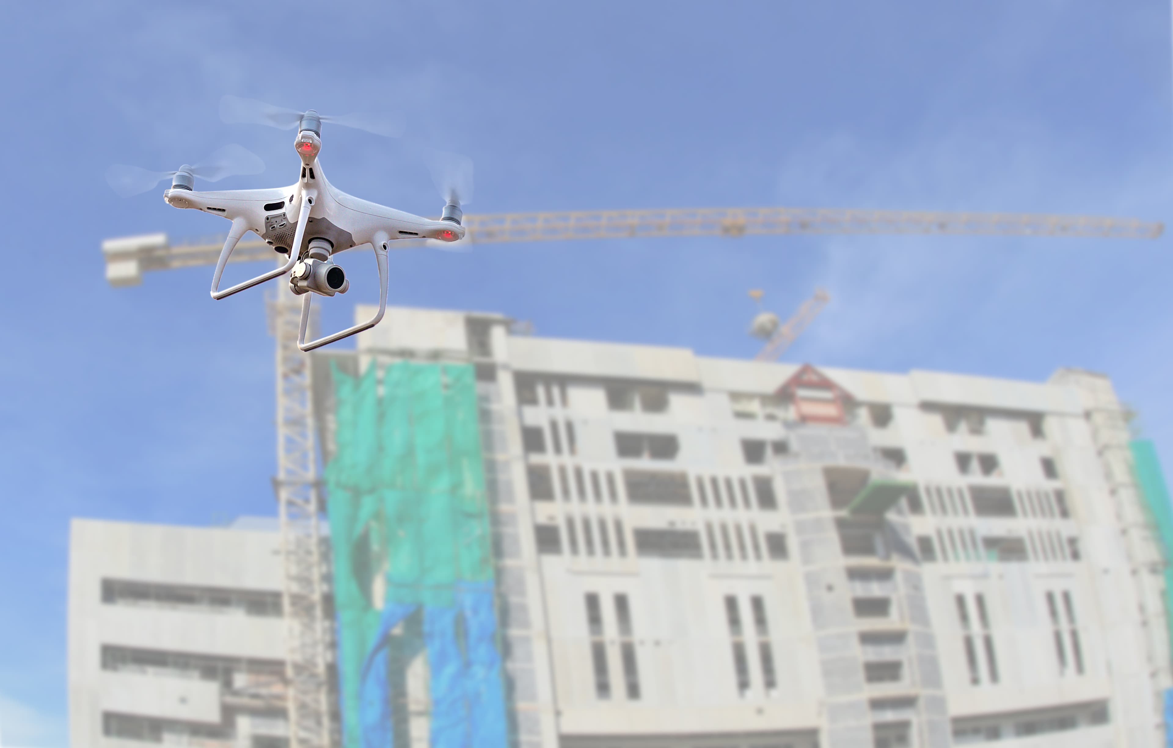 GettyImages-926753944%20%281%29 Drone die boven een bouwplaats vliegt met een kraan en een onafgewerkt gebouw