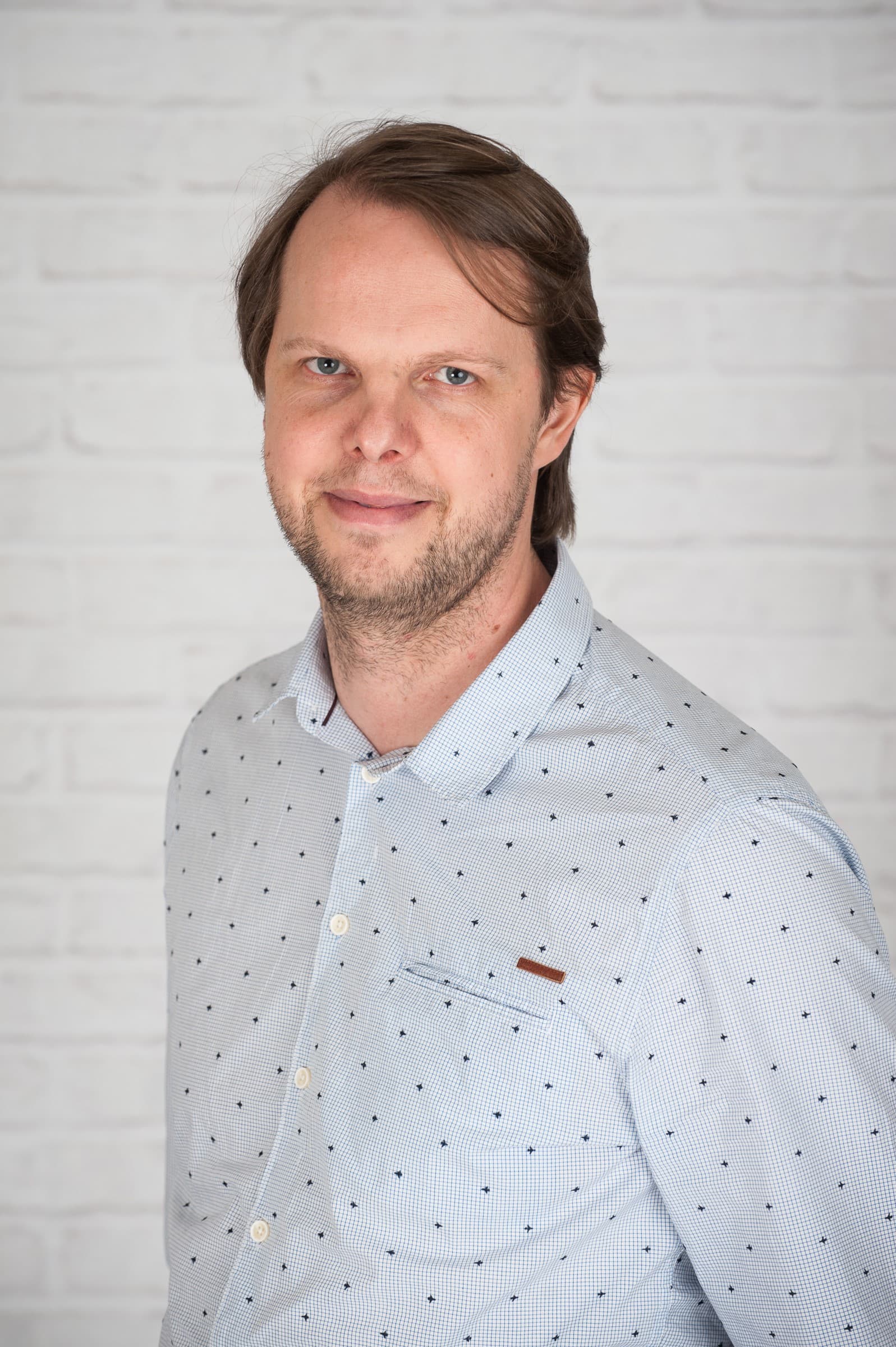 gunther_roelkens_1 Portrait of Gunther Roelkens in a light patterned shirt against a white brick background