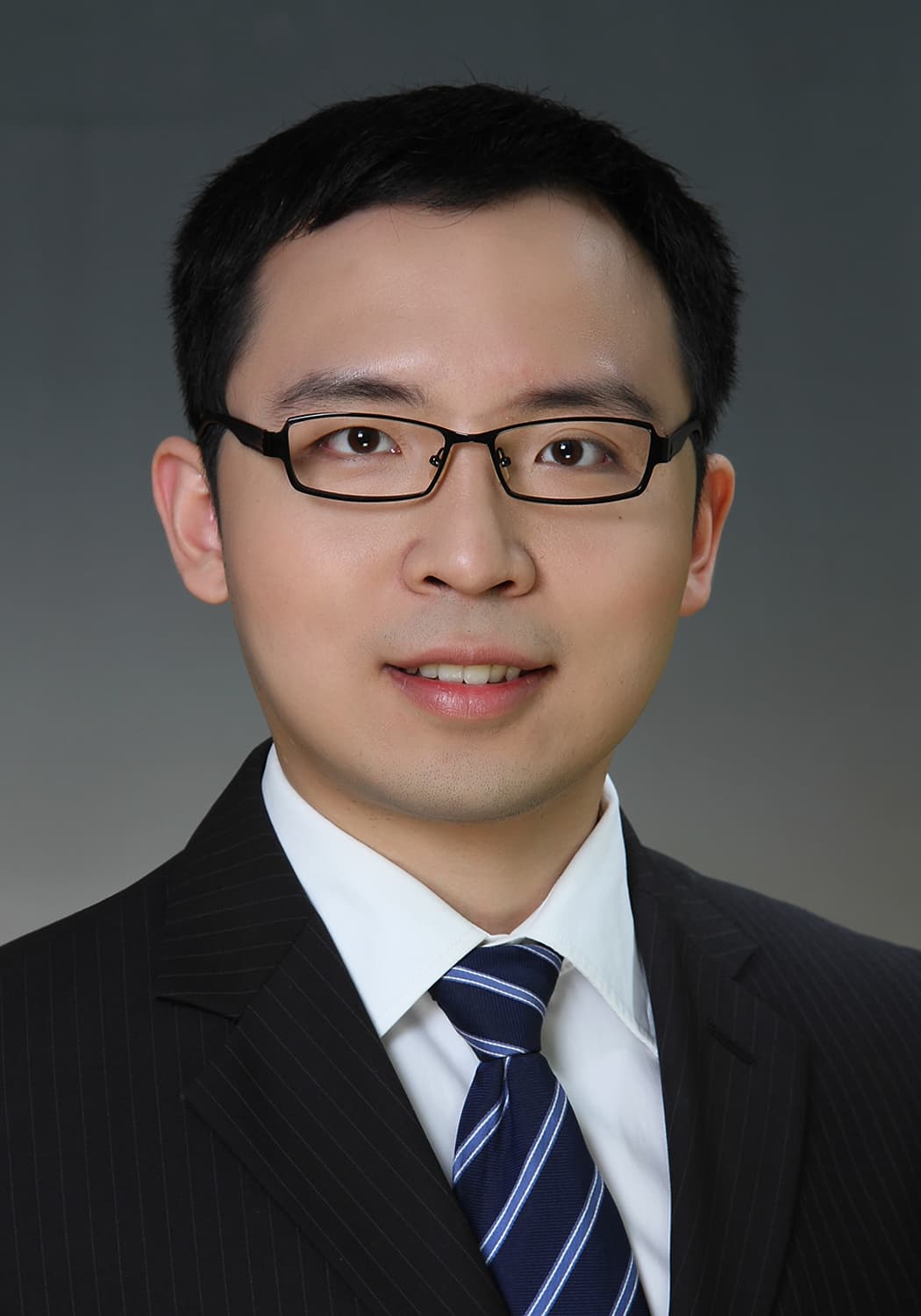 hao_yu_1 Portrait of Hao Yu in a suit and tie, wearing glasses against a gray background