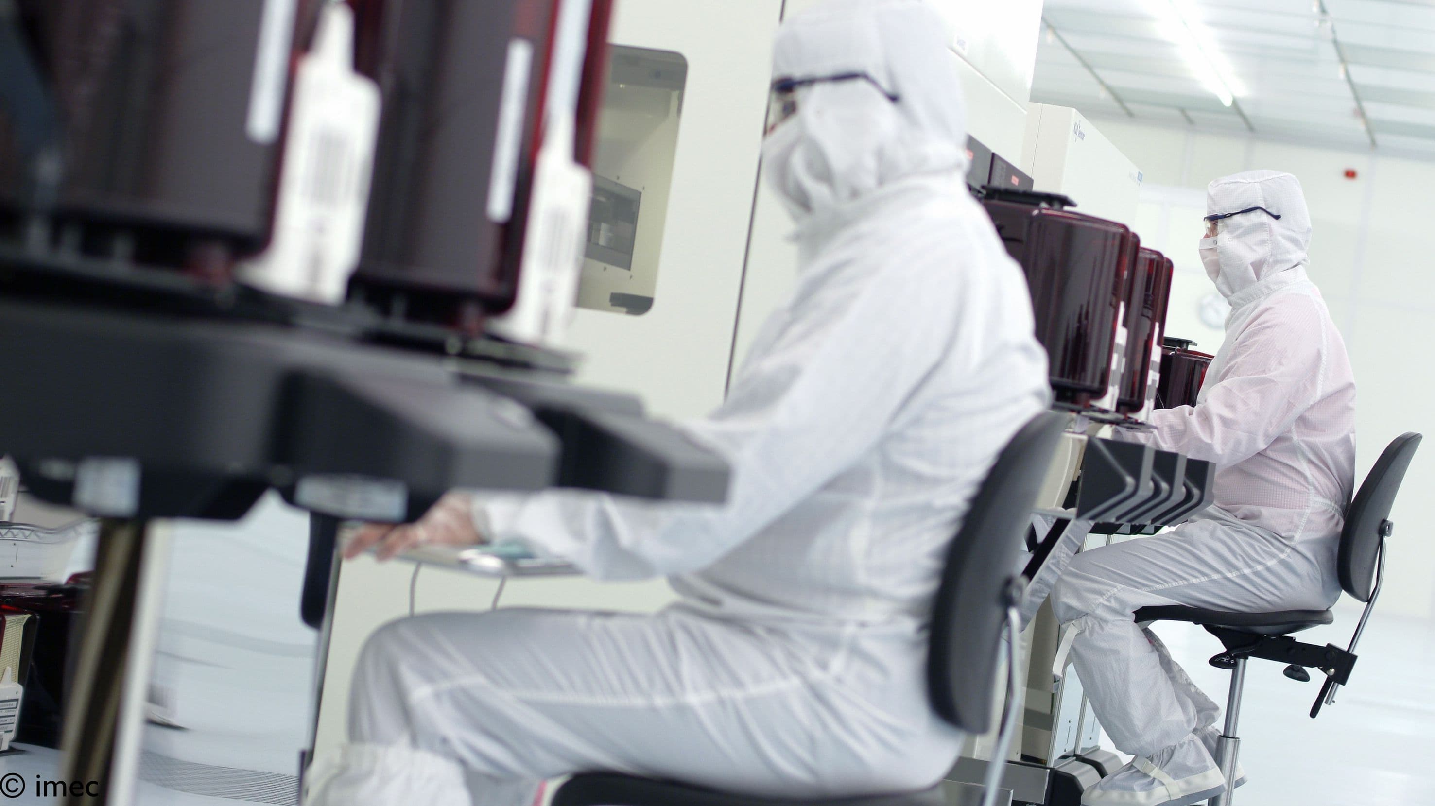 Header_0 Researchers in cleanroom suits work at semiconductor equipment in a cleanroom