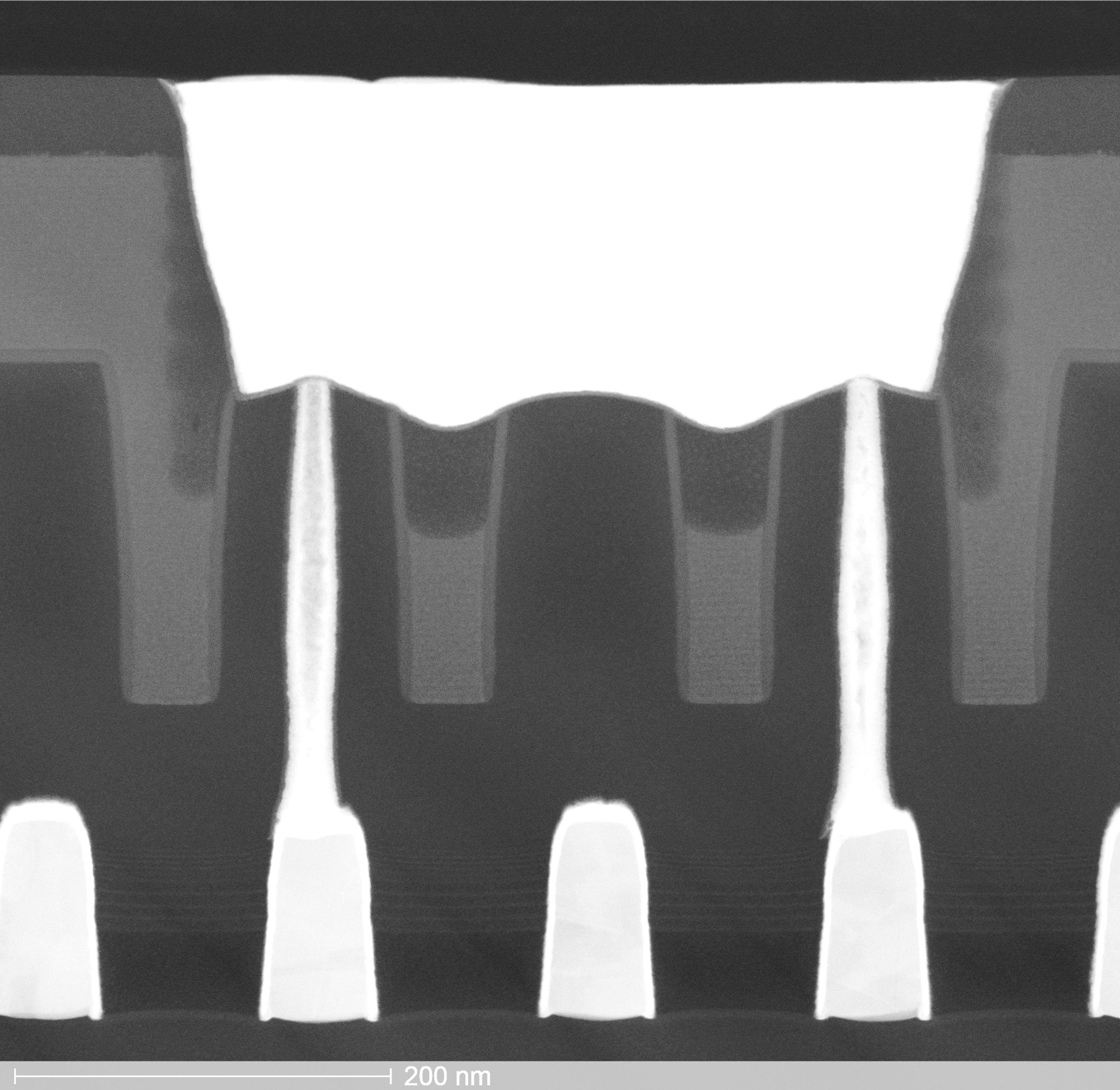 Header_0 Cross-sectional micrograph of a chip structure with vertical interconnects and a 200 nm scale bar