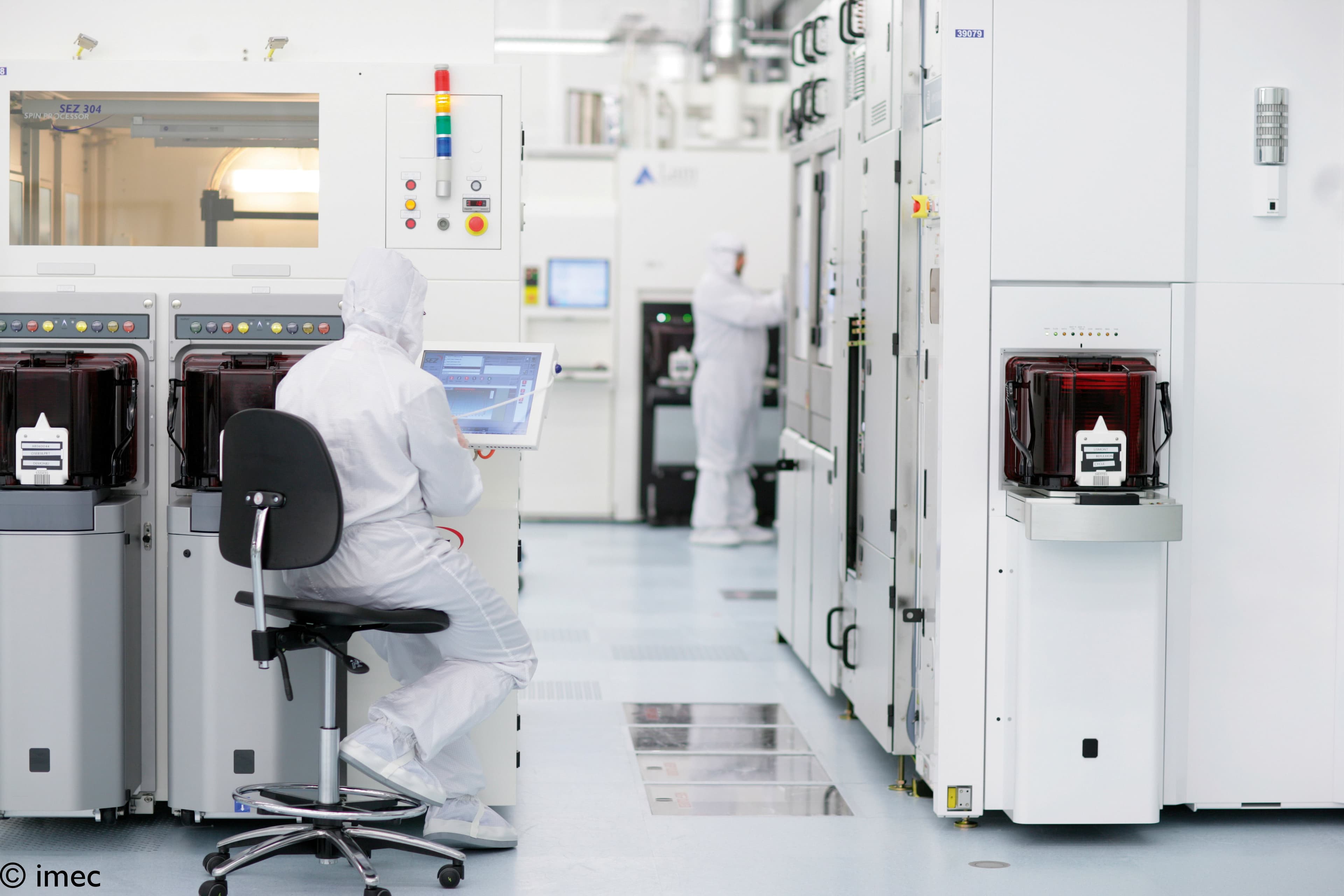 Header%202_0 Cleanroom technicians in white suits operating semiconductor equipment in a bright lab