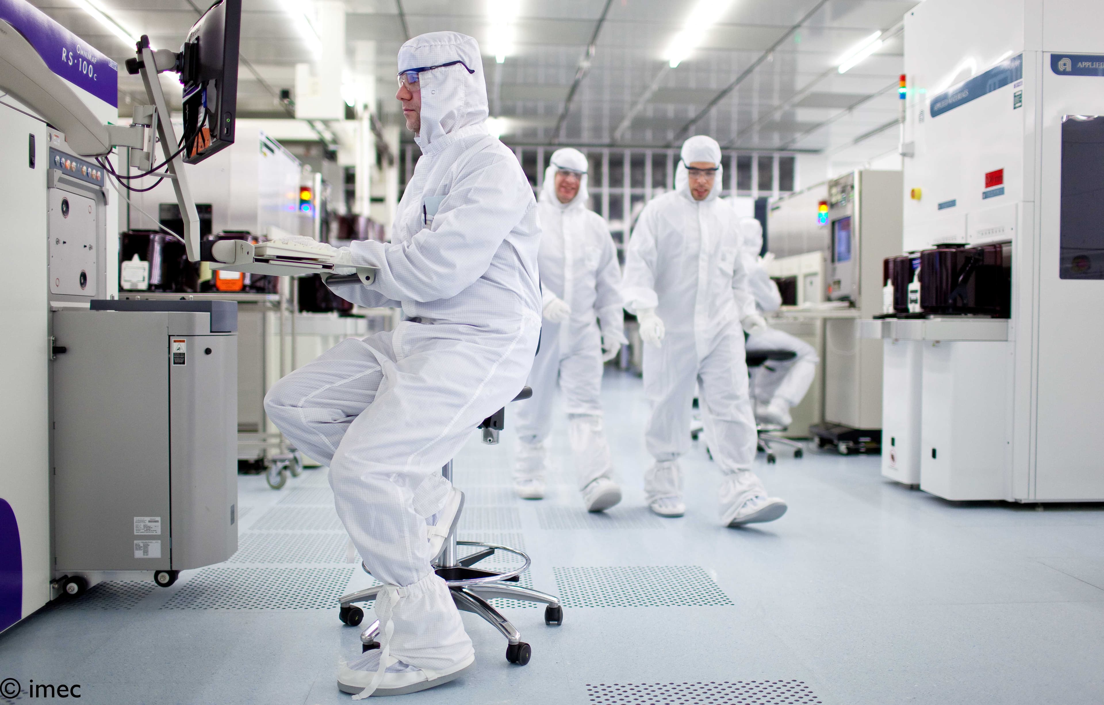 Researchers in cleanroom suits working in semiconductor lab Researchers in cleanroom suits working with semiconductor equipment in a cleanroom lab