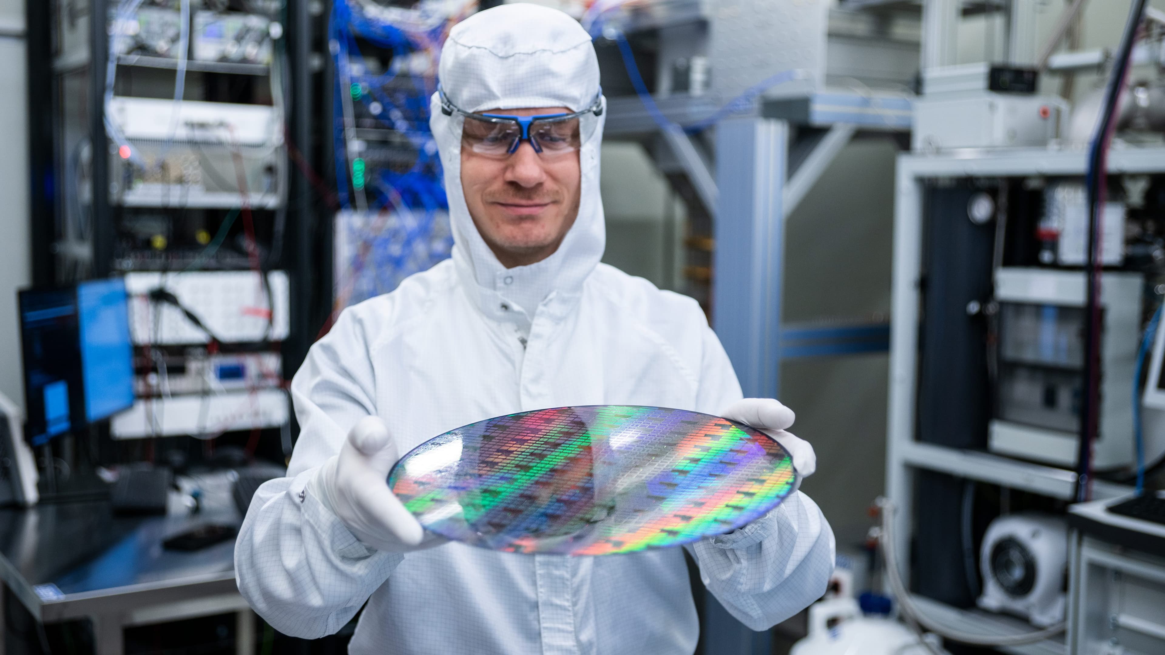 Researcher holding silicon wafer in cleanroom Researcher in a cleanroom holding a large silicon wafer with rainbow reflections