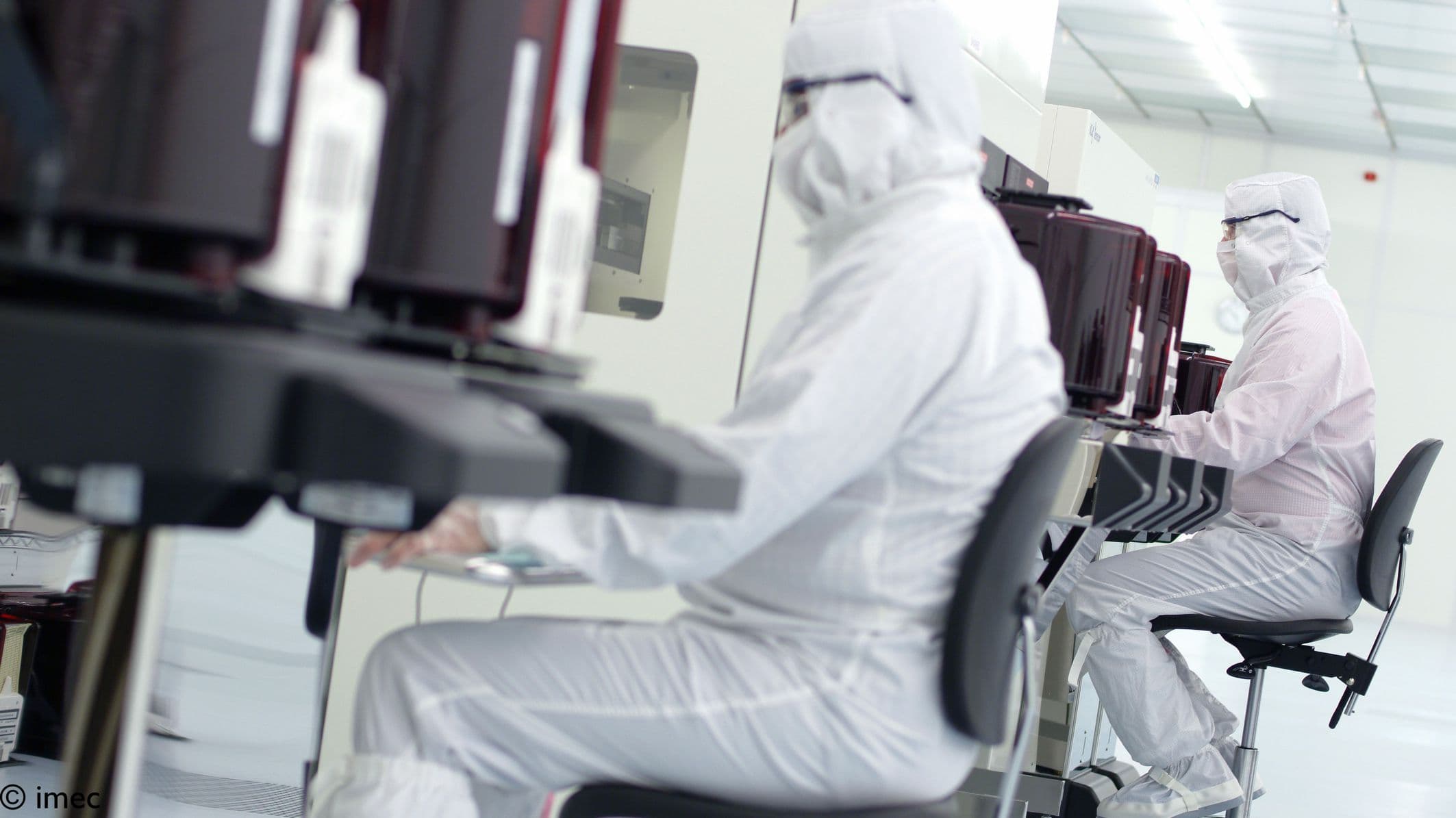 Researchers working in semiconductor cleanroom Researchers in cleanroom suits working at semiconductor equipment in a cleanroom