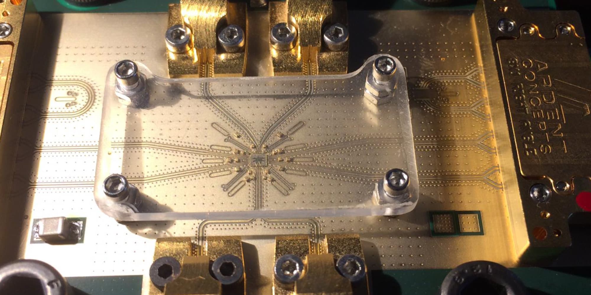 Microscope view of semiconductor chip test setup Microscope view of a mounted semiconductor chip test setup with gold connectors and a transparent clamp