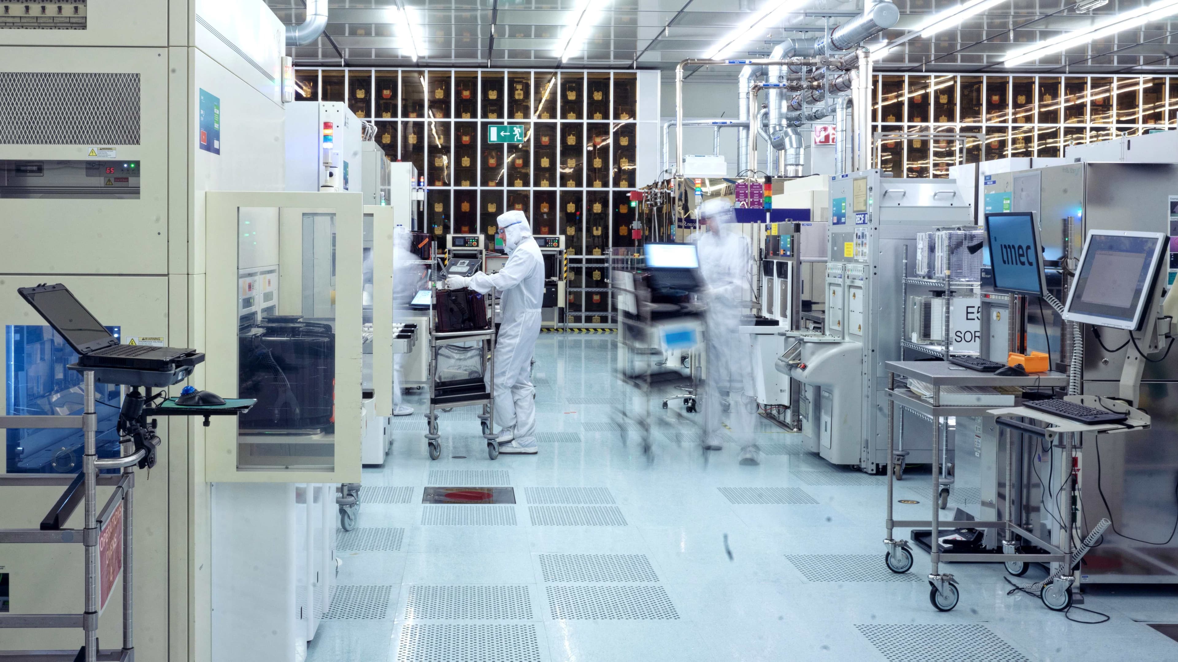 header Researchers in a cleanroom operating semiconductor equipment among lab tools and monitors