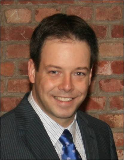 Herman_Oprins_foto_1 Portrait of Herman Oprins in a suit and tie against a brick wall