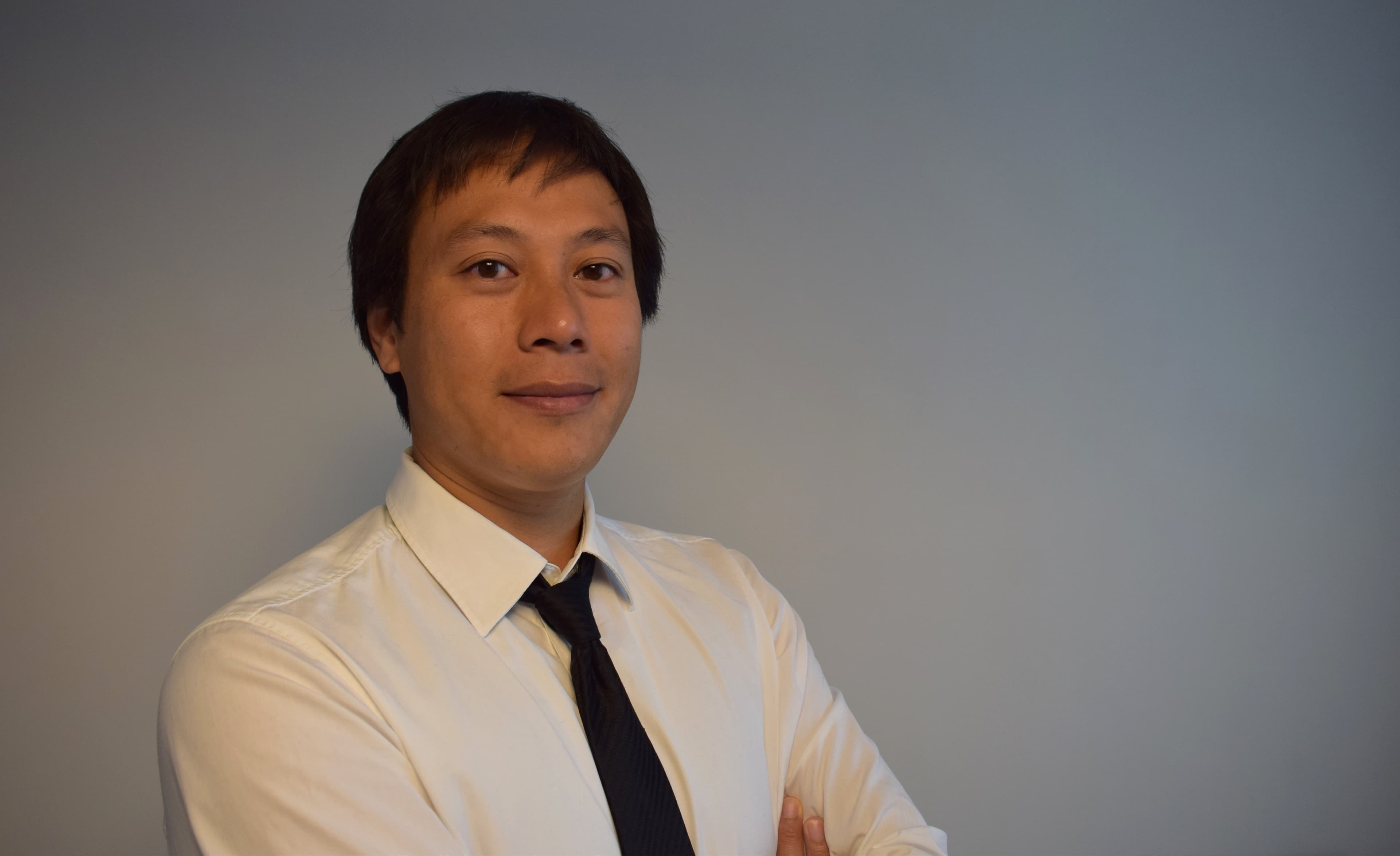 HiepLuong_1 Portrait of Hiep Luong in a white shirt and black tie against a plain gray background