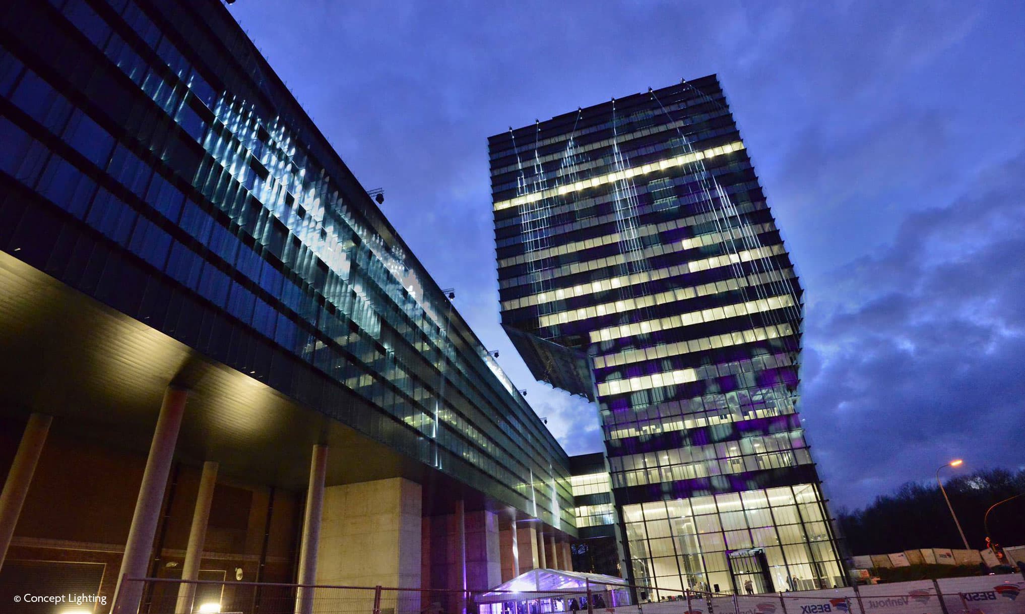 highlights-tower_1 Modern imec office towers lit up at dusk against a cloudy sky