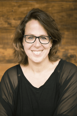 Ilse-Mari%C3%ABn Portret van Ilse Mariën die glimlacht tegen een houten achtergrond