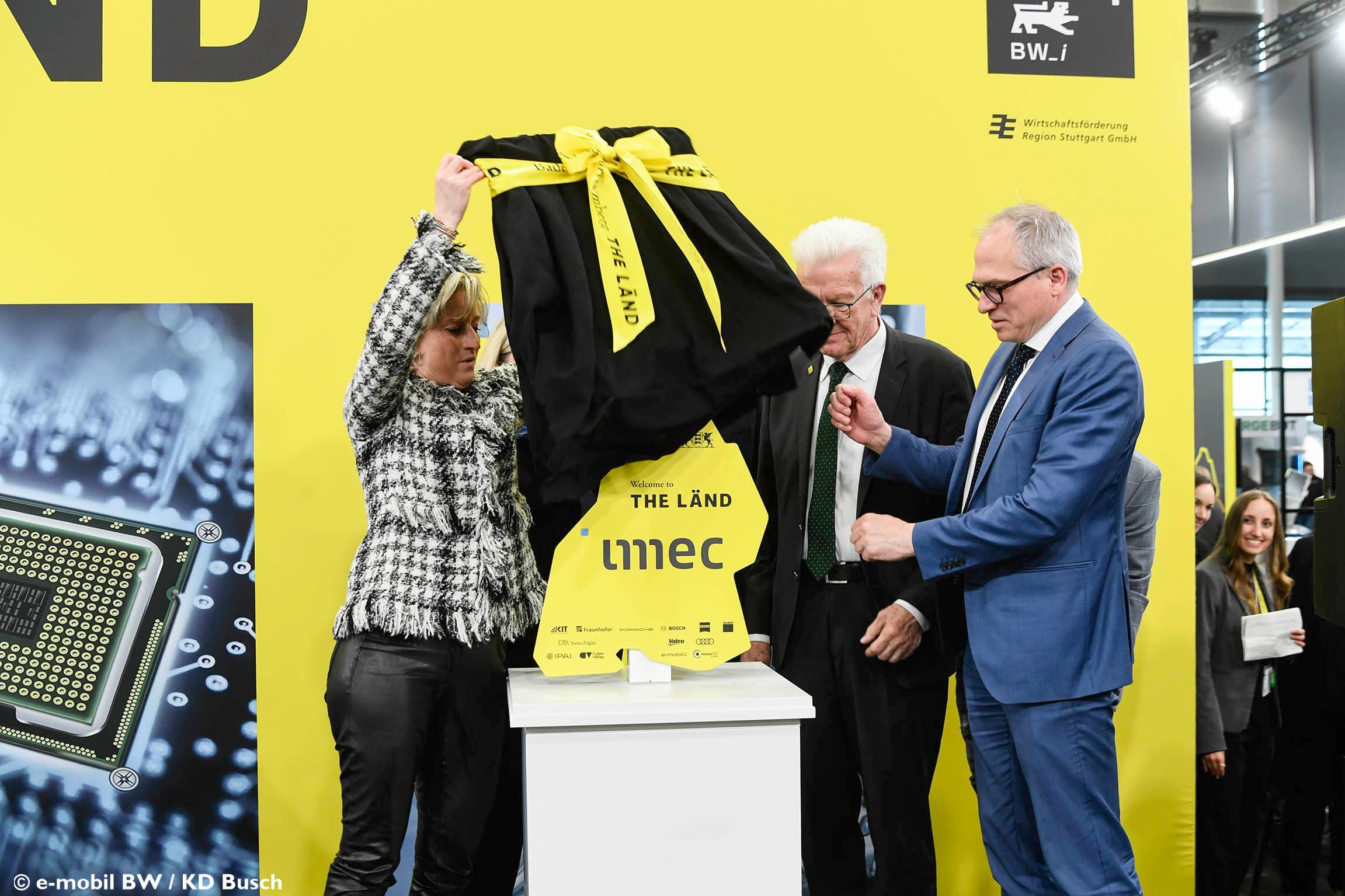 Officials unveiling an imec sign at launch event Three officials unveil an imec sign on a pedestal at a launch event with a yellow backdrop.