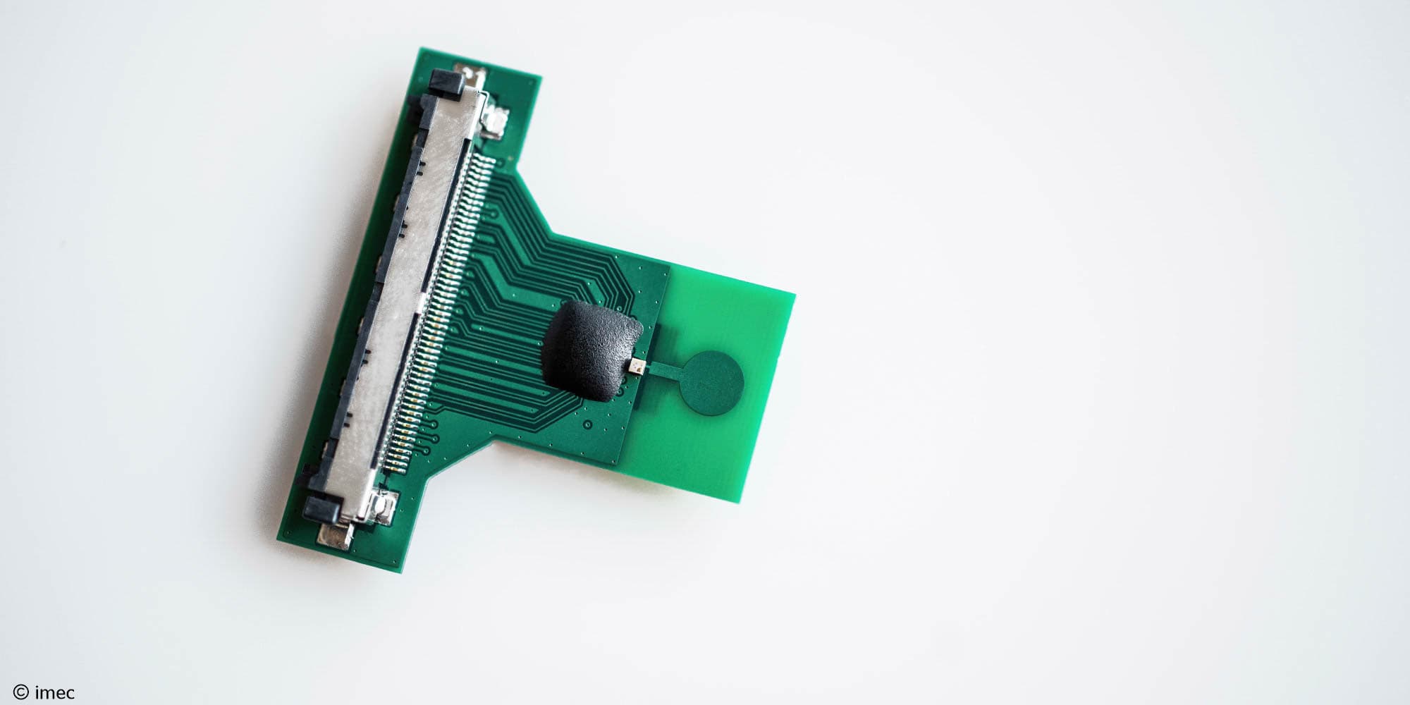 Green circuit board with metal connector and sensor pad Green circuit board with a metal connector and a round sensor pad, shown on a white background