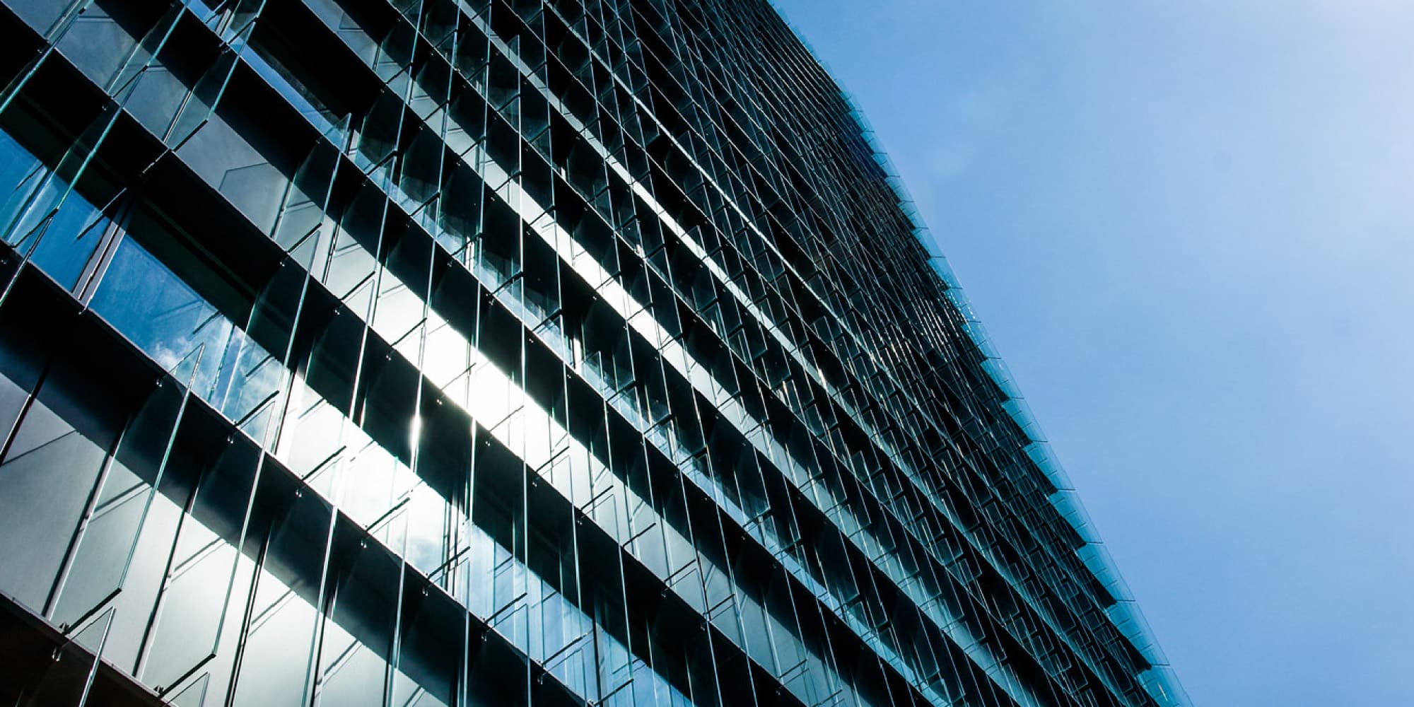 imec_1 Low-angle view of a modern glass office building against a blue sky