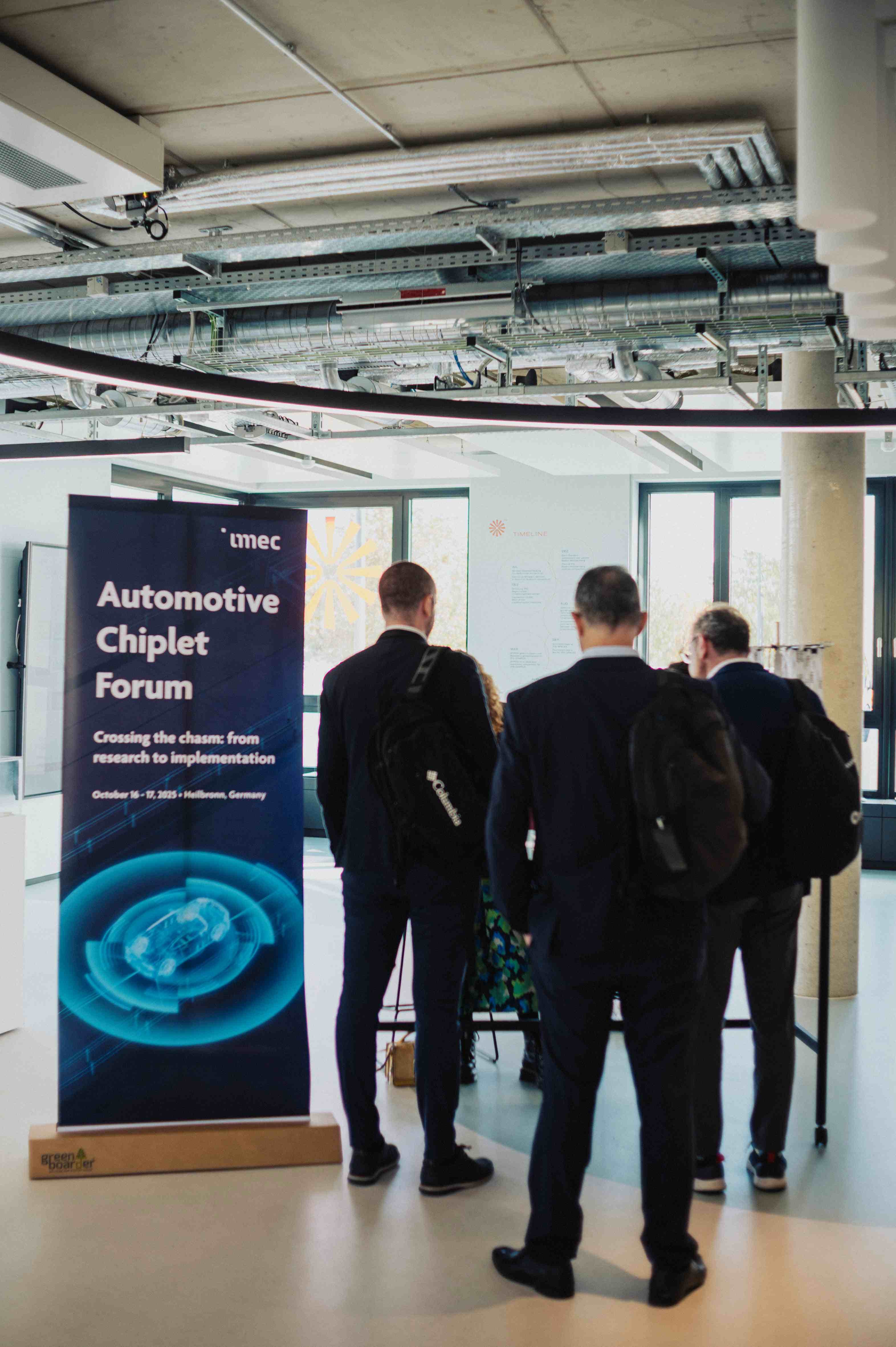Imec%20ACF%20Fall_2 Attendees in a modern venue stand beside a banner for the Automotive Chiplet Forum