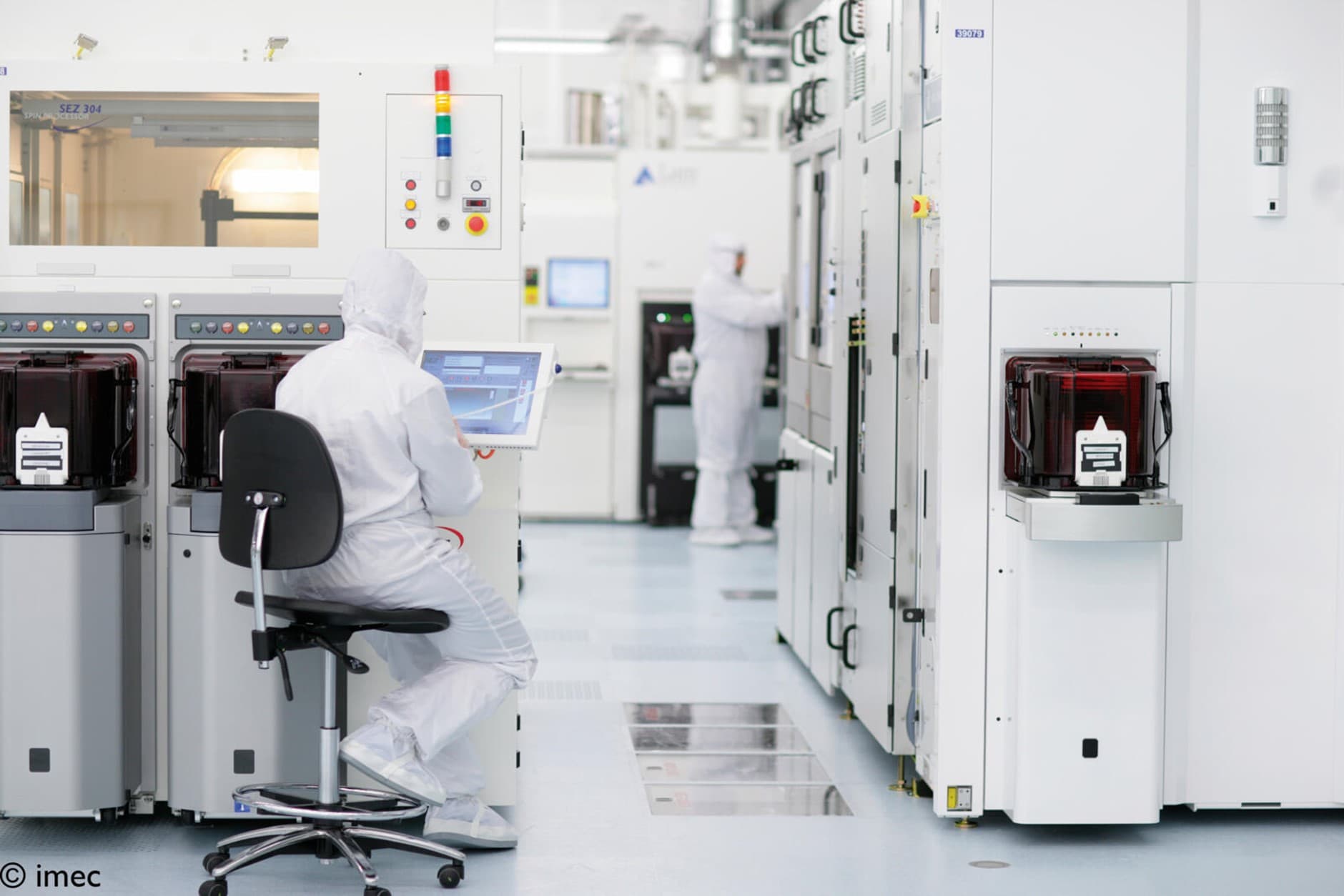 Imec%20cleanroom Researchers in white cleanroom suits operating semiconductor equipment inside imec’s cleanroom