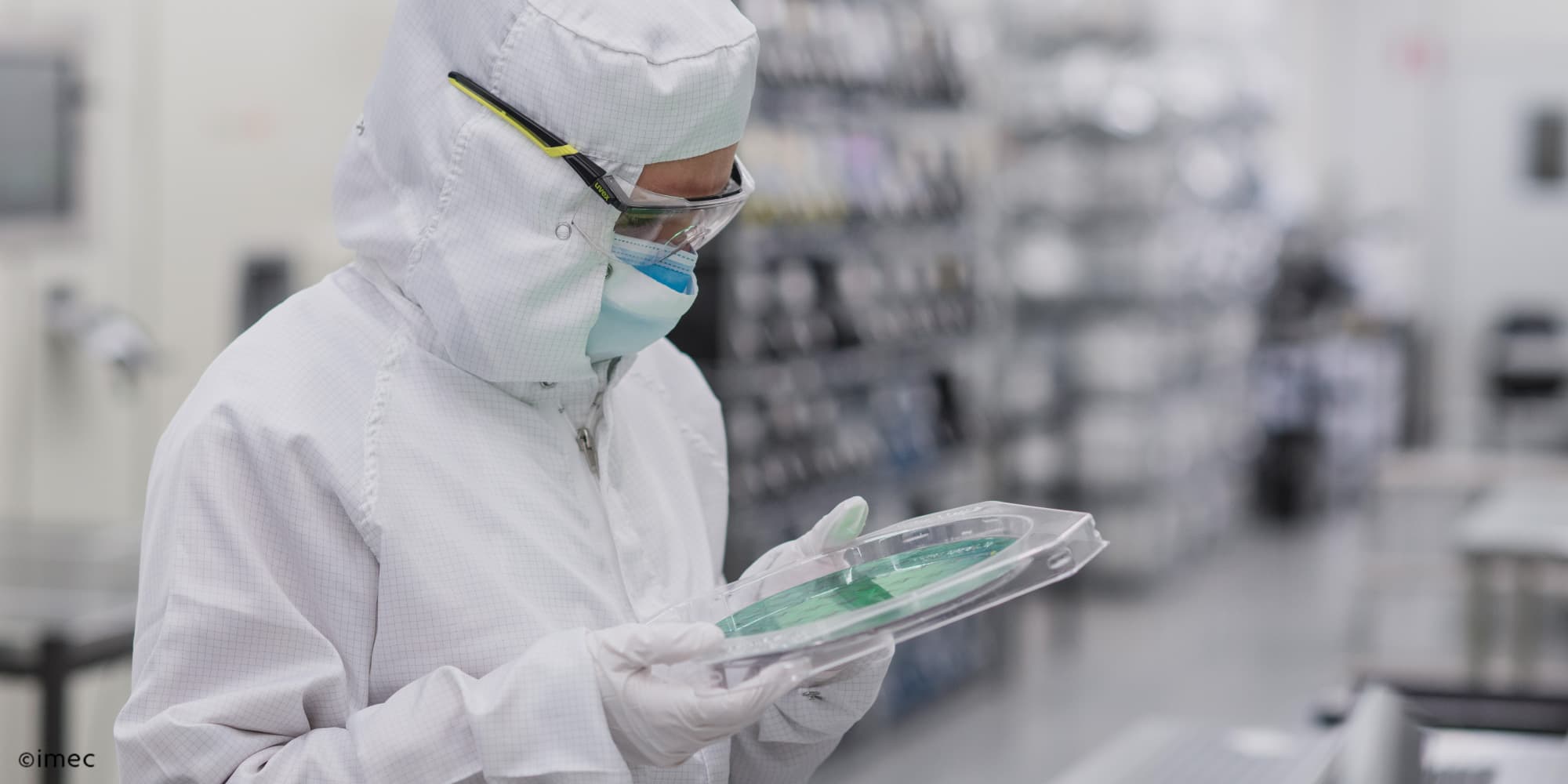 Imec-and-AIXTRON-Demonstrate-200-mm-GaN-Epitaxy-on-AIX-G5%2B-C-for-1200V-Applications-with-Breakdown-in-Excess-of-1800V_0 Cleanroom researcher in protective suit inspecting a wafer in a semiconductor lab.