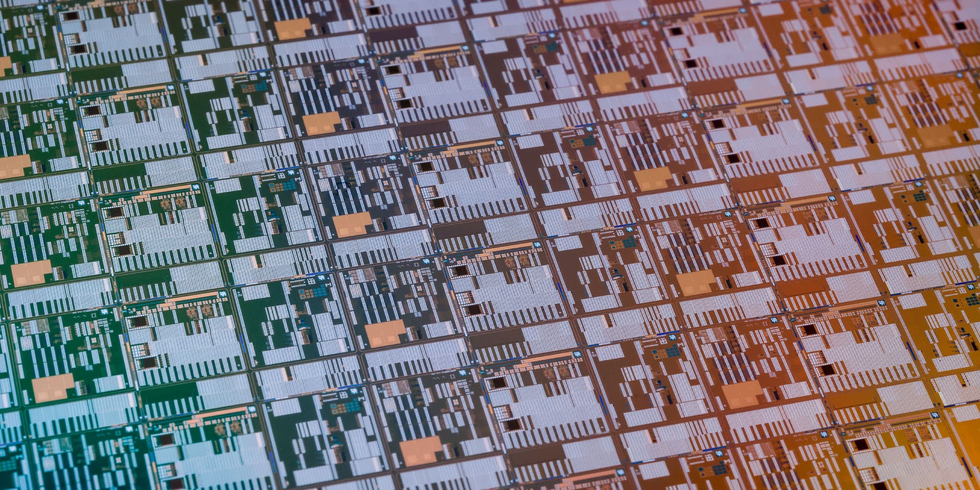 imec-development-advanced-logic-memory-technology-processing_1 Close-up of a semiconductor wafer with repeated chip patterns in green, gray and orange