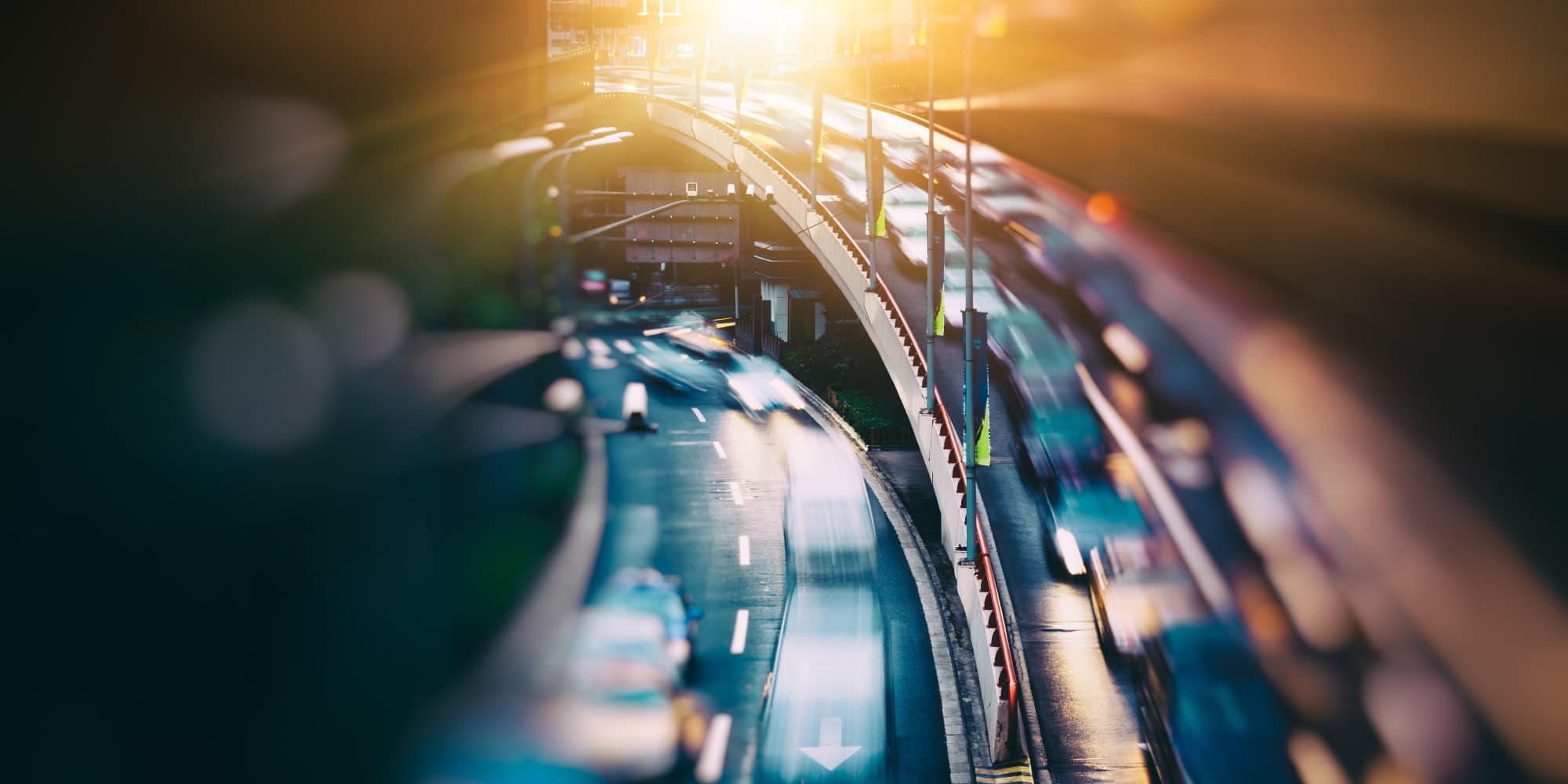 Imec-enables-vehicles-to-work-together%2C-creating-smoother-and-safer-traffic-flows_1 Blurred traffic on a curved urban road at sunset, suggesting connected vehicles and smoother flow