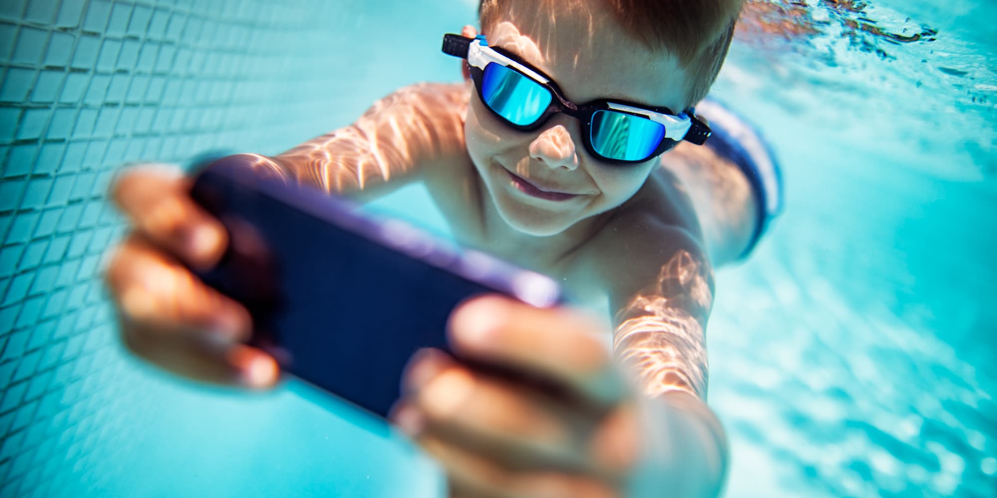 imec-magazine-0218-analog-rf_1 Smiling child underwater holding a smartphone toward the camera