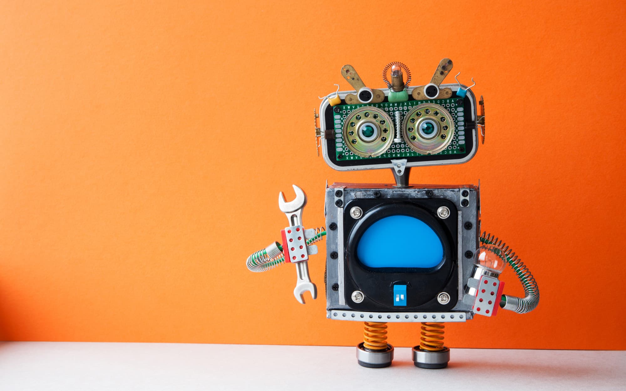 imec-magazine-0318-cover_1 Toy robot made from electronic parts against an orange background